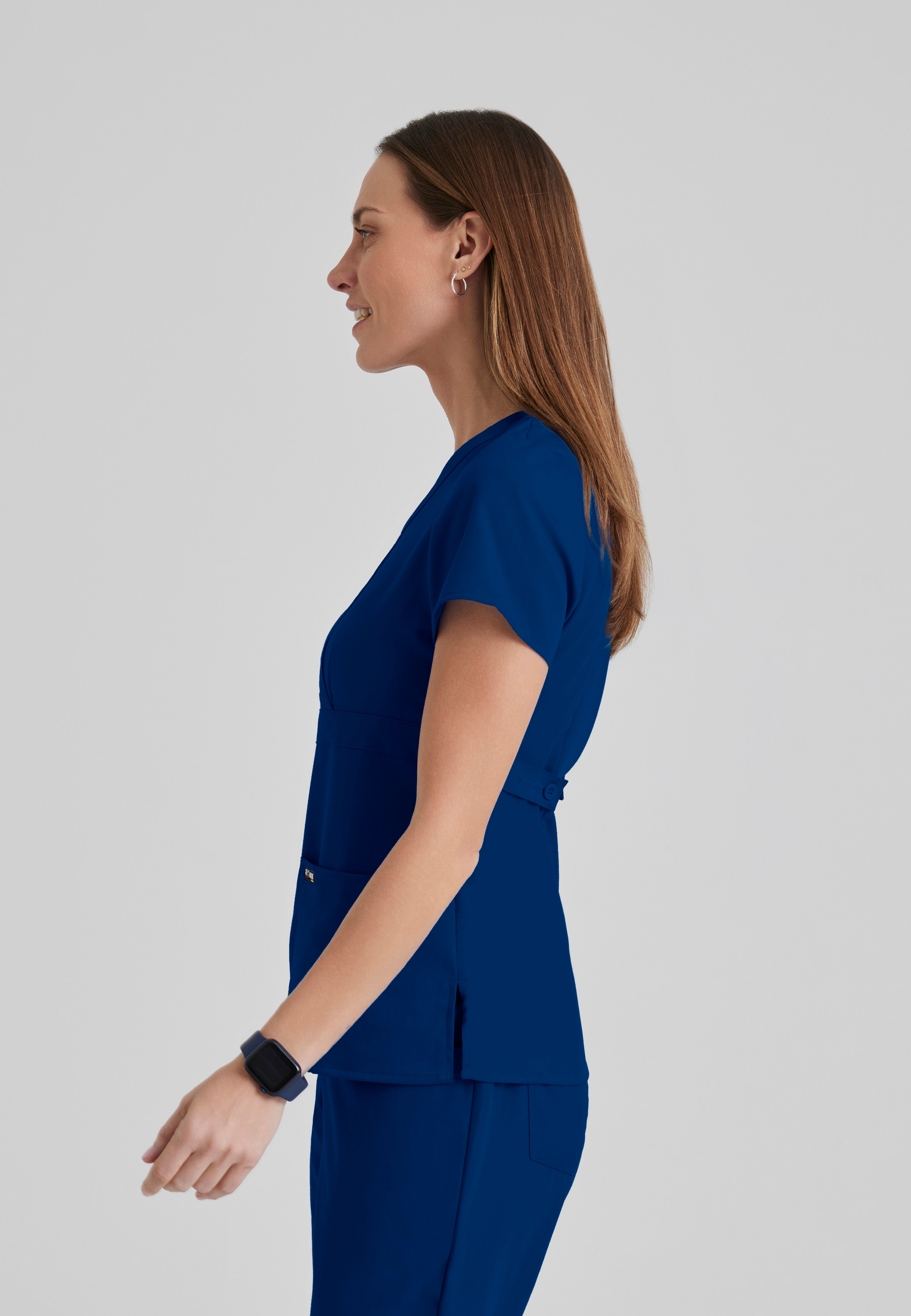 Side View of the Riley 3-Pocket Mock Wrap V-Neck Scrub Top in Indigo from Grey's Anatomy™ by Barco Classic