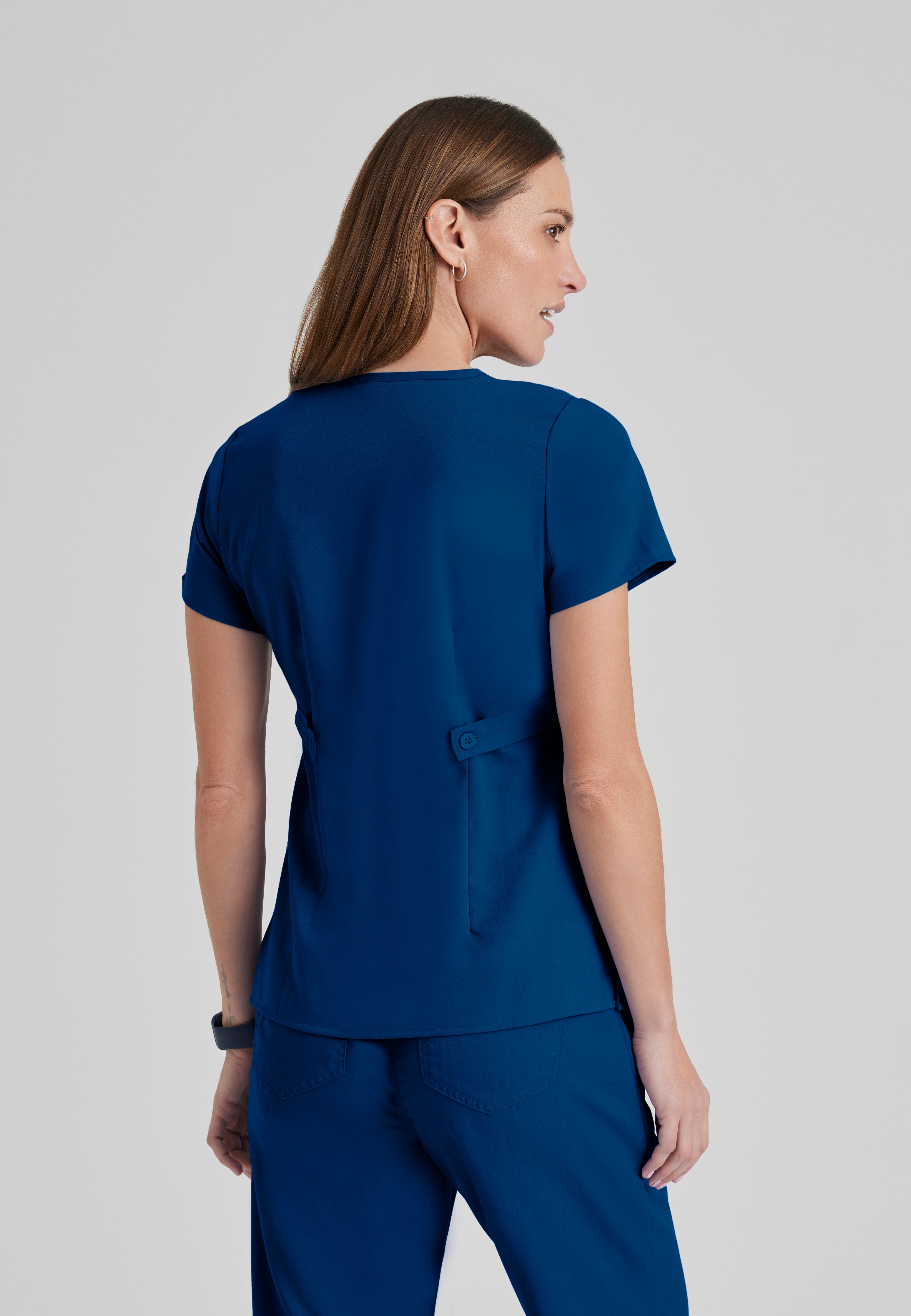 Back View of the Riley 3-Pocket Mock Wrap V-Neck Scrub Top in Indigo from Grey's Anatomy™ by Barco Classic