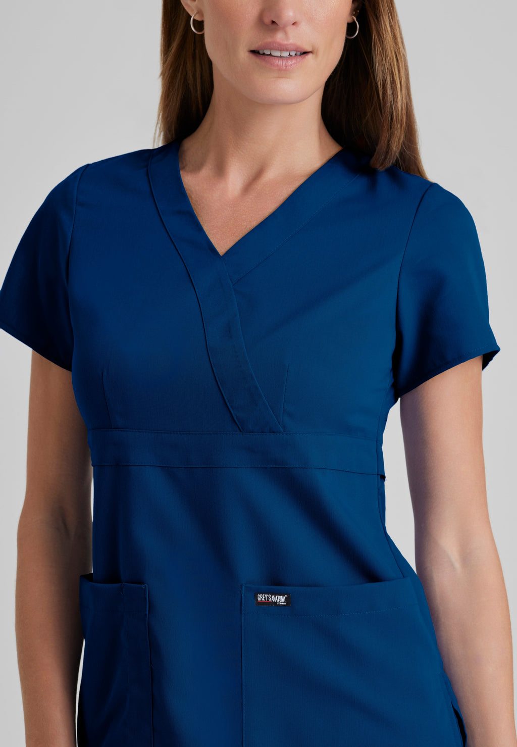 Detail Shot of the Riley 3-Pocket Mock Wrap V-Neck Scrub Top in Indigo from Grey's Anatomy™ by Barco Classic