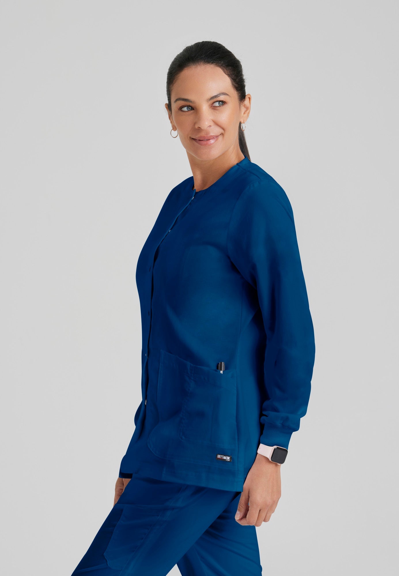 Side View of the Jamie 4-Pocket Crewneck Snap-Front Scrub Jacket in Indigo from Grey's Anatomy™ by Barco Classic