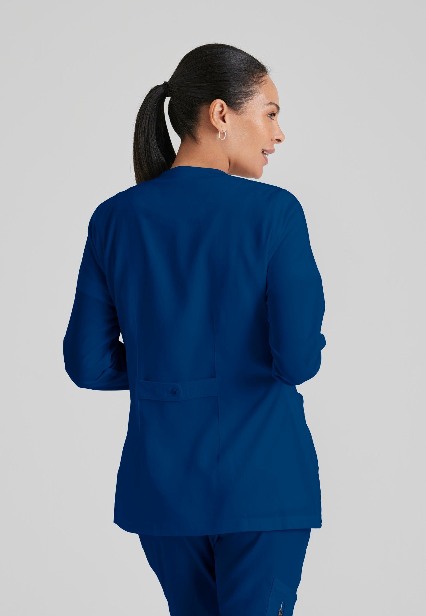 Back View of the Jamie 4-Pocket Crewneck Snap-Front Scrub Jacket in Indigo from Grey's Anatomy™ by Barco Classic