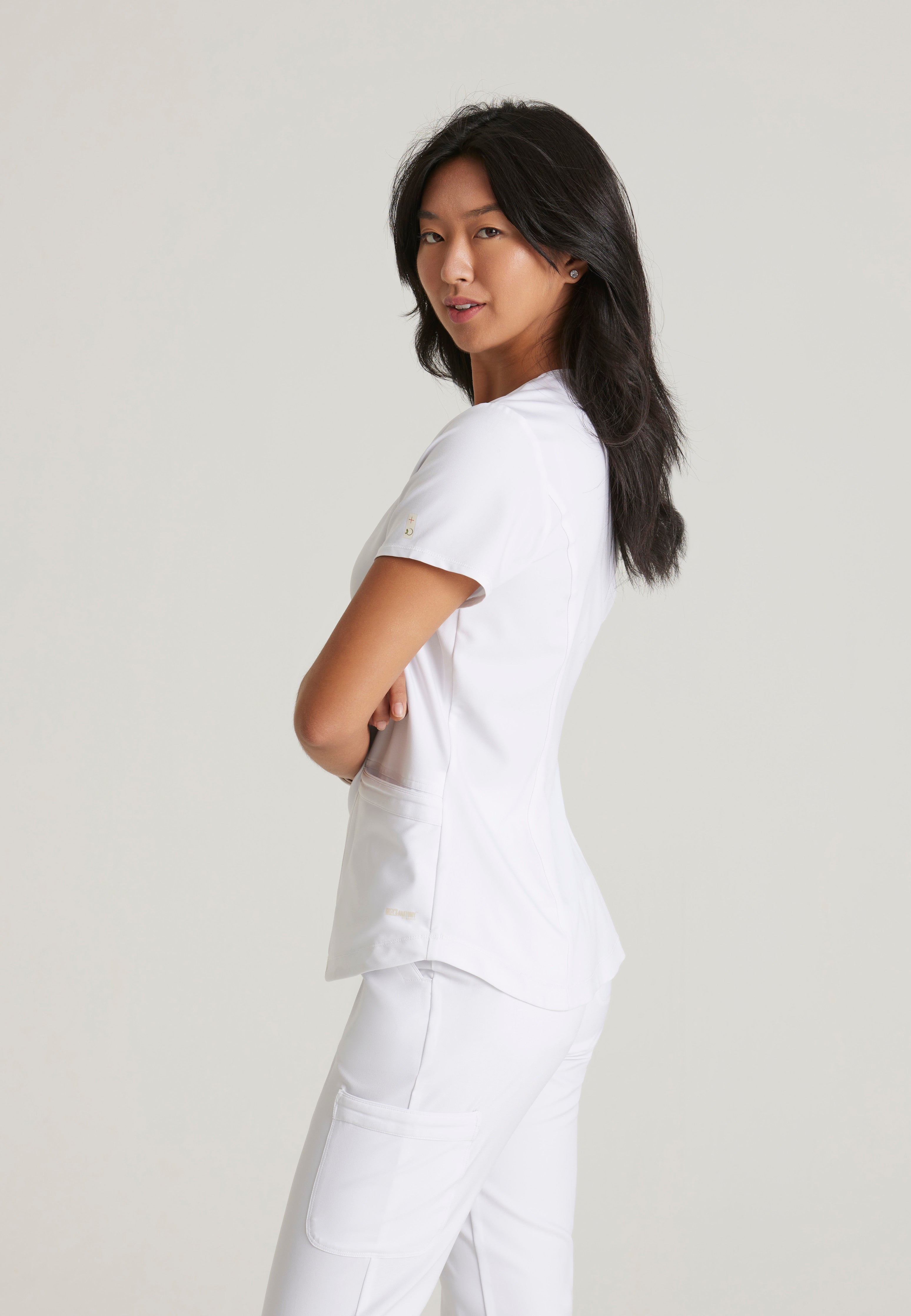 Side View of the Rhythm 2-Pocket Ciclo® Scrub Top in White from Grey's Anatomy™ by Barco Evolve