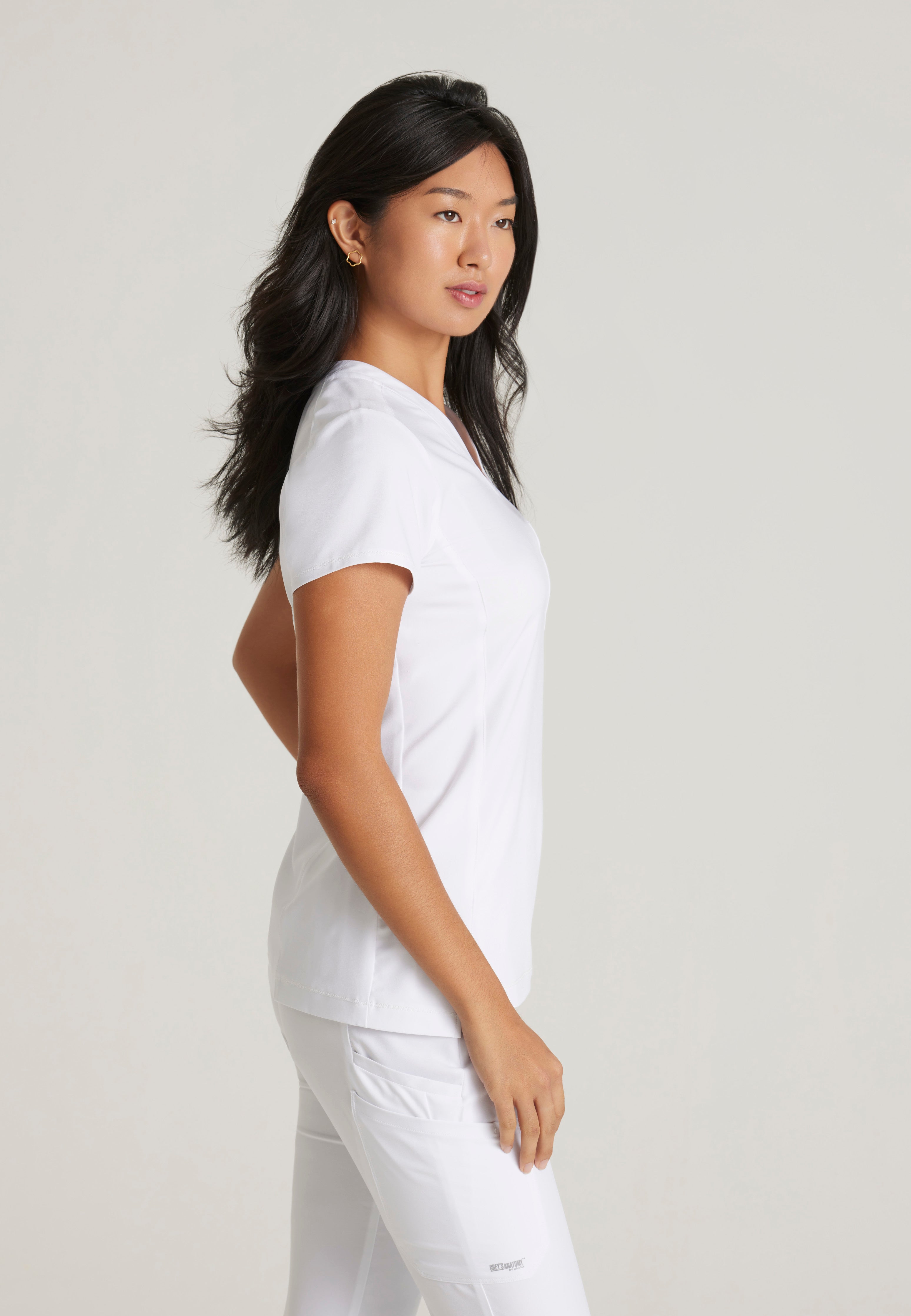 Side View of the Sway 1-Pocket Banded V-Neck Ciclo® Scrub Top in White from Grey's Anatomy™ by Barco Evolve