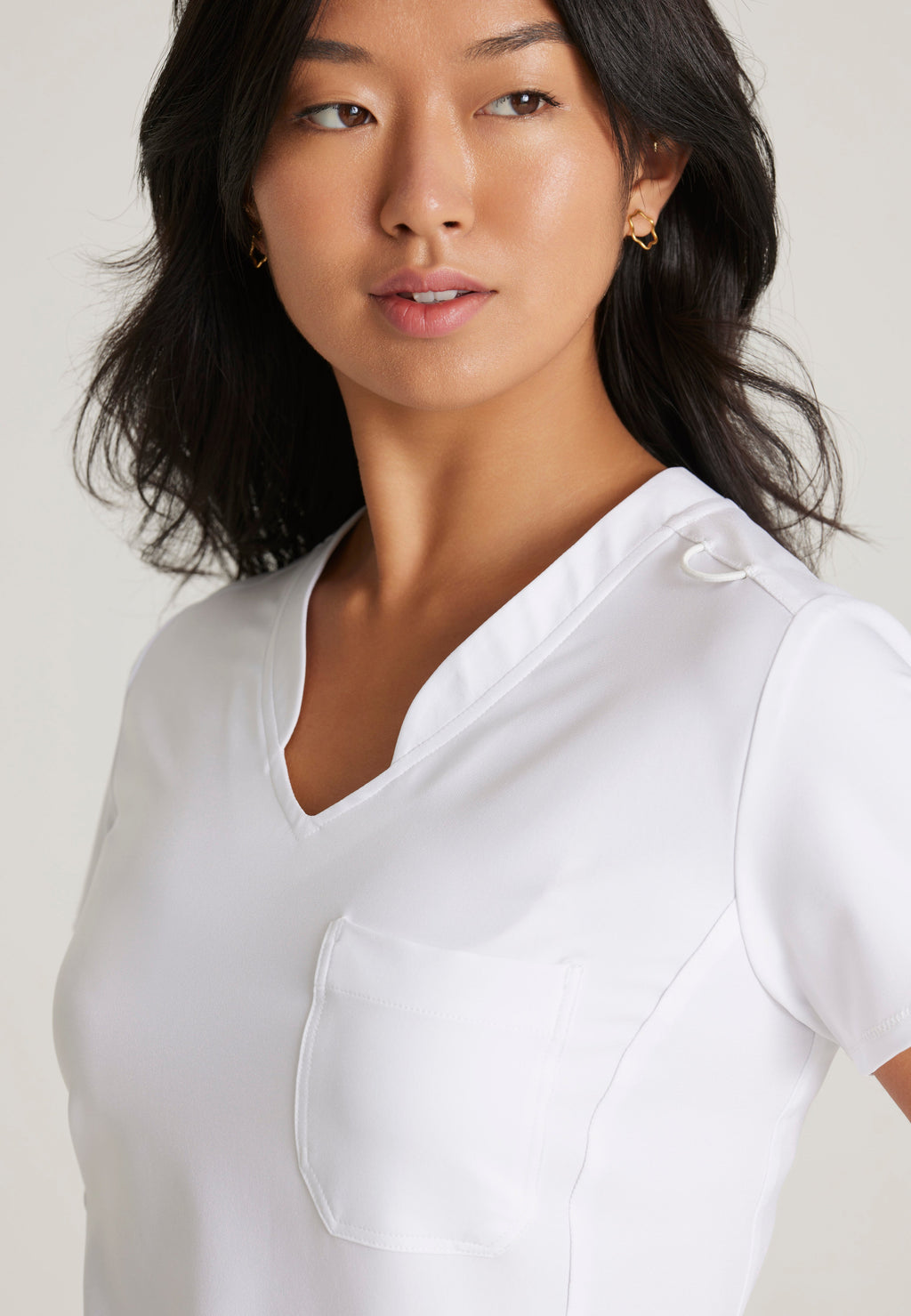 Detail Shot of the Sway 1-Pocket Banded V-Neck Ciclo® Scrub Top in White from Grey's Anatomy™ by Barco Evolve