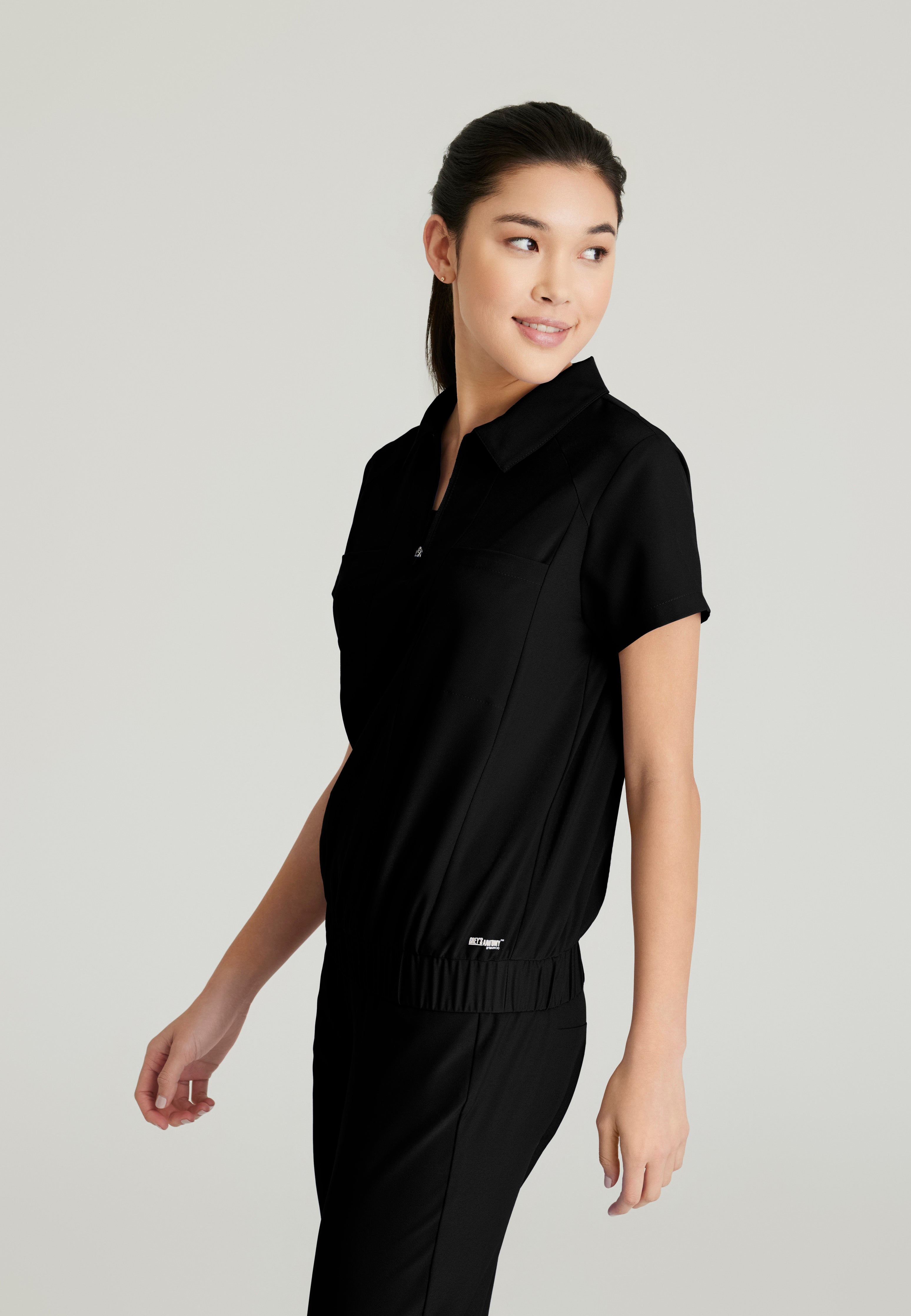 Side View of the Perseverance 2-Pocket Zip Neck Banded Waist Top in Black from Grey's Anatomy™ by Barco Evolve
