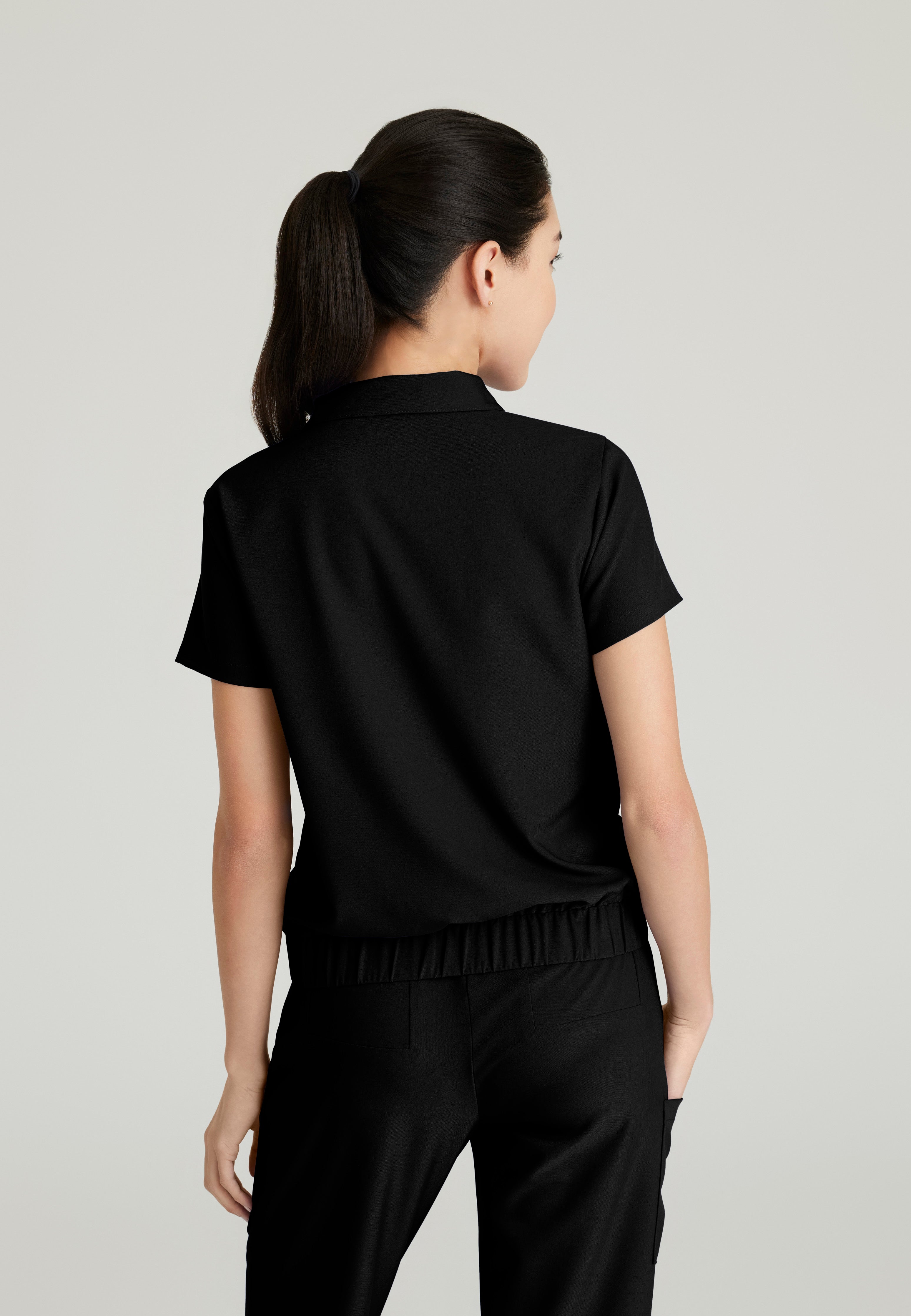 Back View of the Perseverance 2-Pocket Zip Neck Banded Waist Top in Black from Grey's Anatomy™ by Barco Evolve