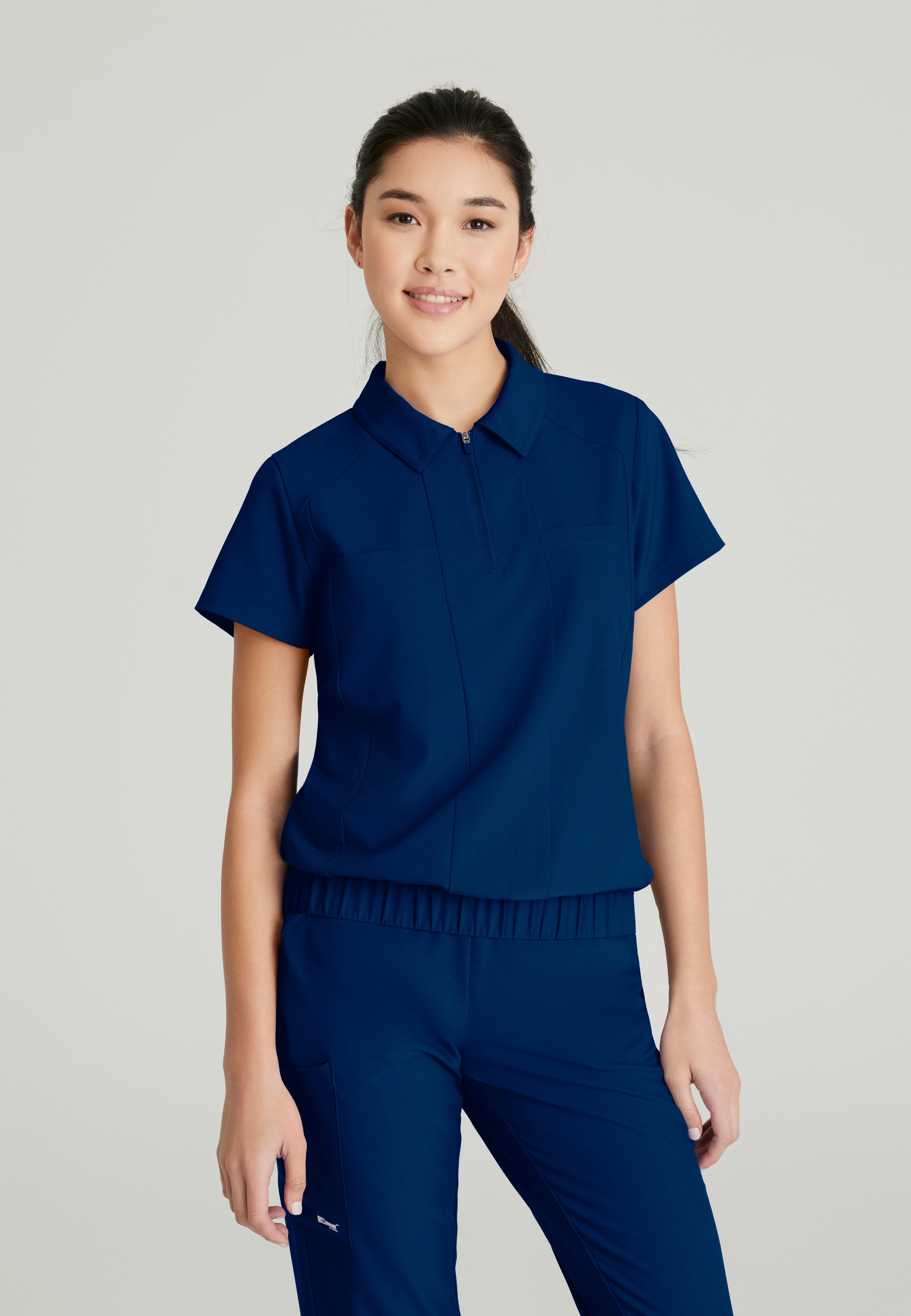 Front View of the Perseverance 2-Pocket Zip Neck Banded Waist Top in Indigo from Grey's Anatomy™ by Barco Evolve