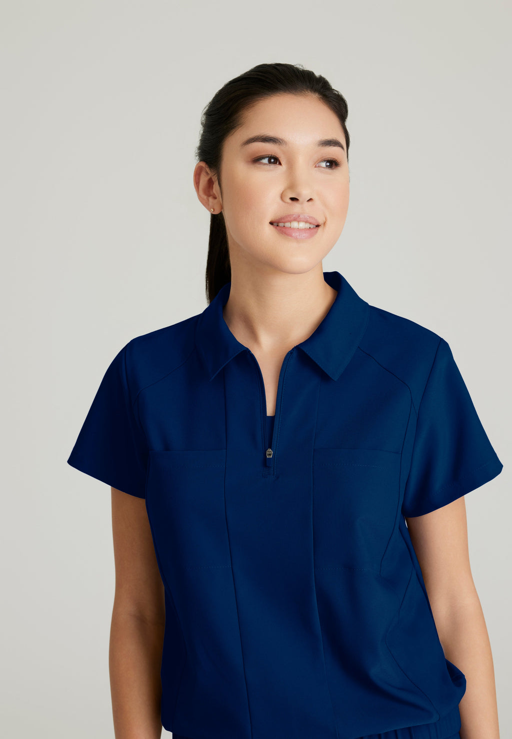 Detail Shot of the Perseverance 2-Pocket Zip Neck Banded Waist Top in Indigo from Grey's Anatomy™ by Barco Evolve