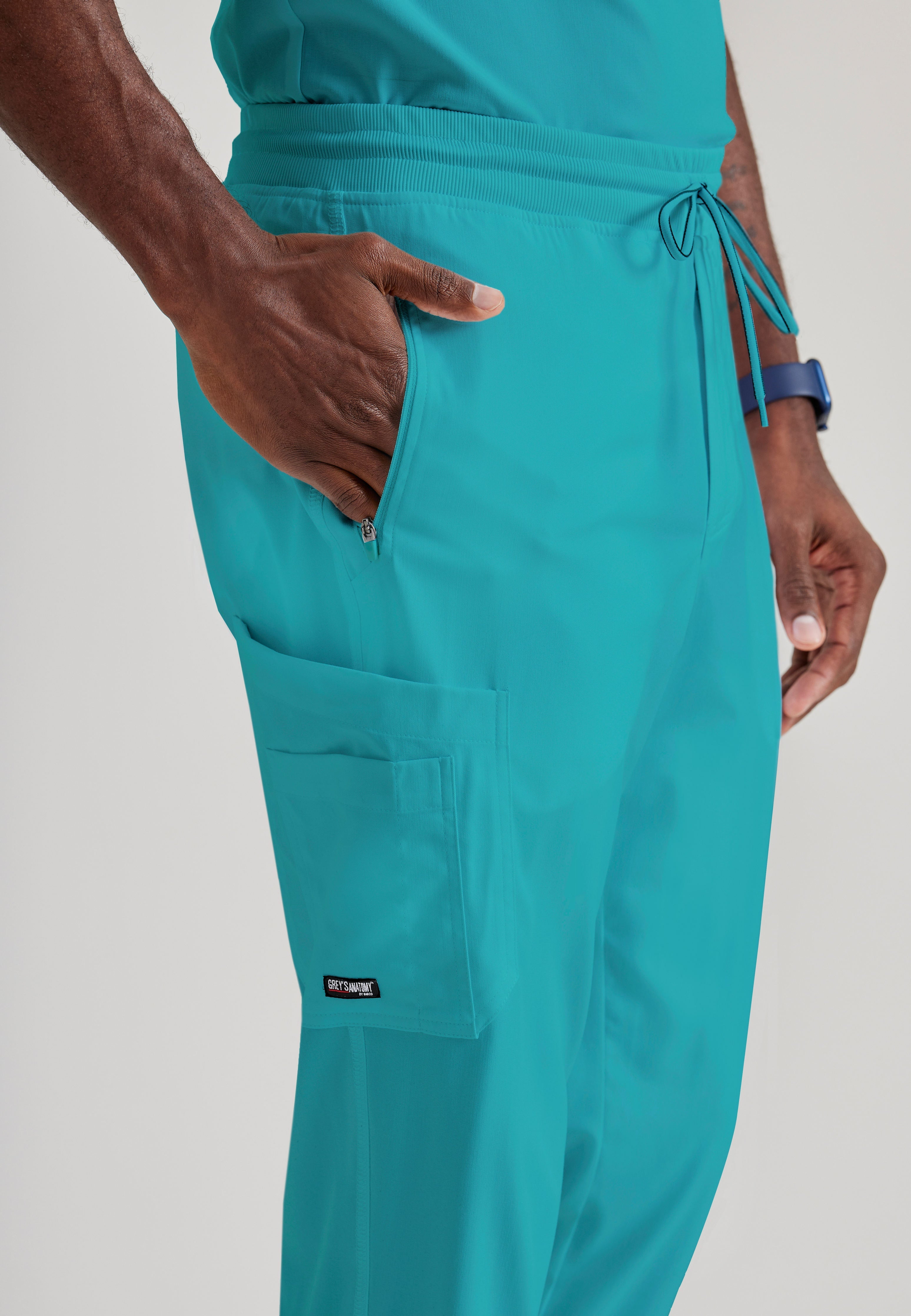 Grey's Anatomy Spandex-Stretch Men’s teal Zip-Fly 5-Pocket Jogger Scrub Pant. Elastic waistband with drawstring. Wrinkle-resistant, easy care fabric. 