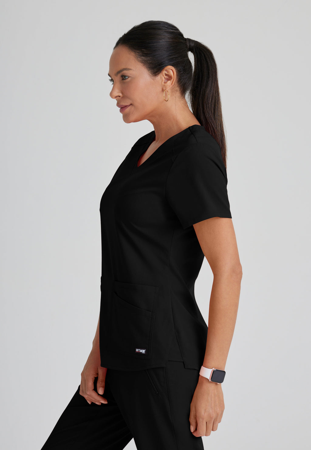 Side View of the Emma 4-Pocket V-Neck Scrub Top in Black from Grey's Anatomy™ by Barco Spandex Stretch