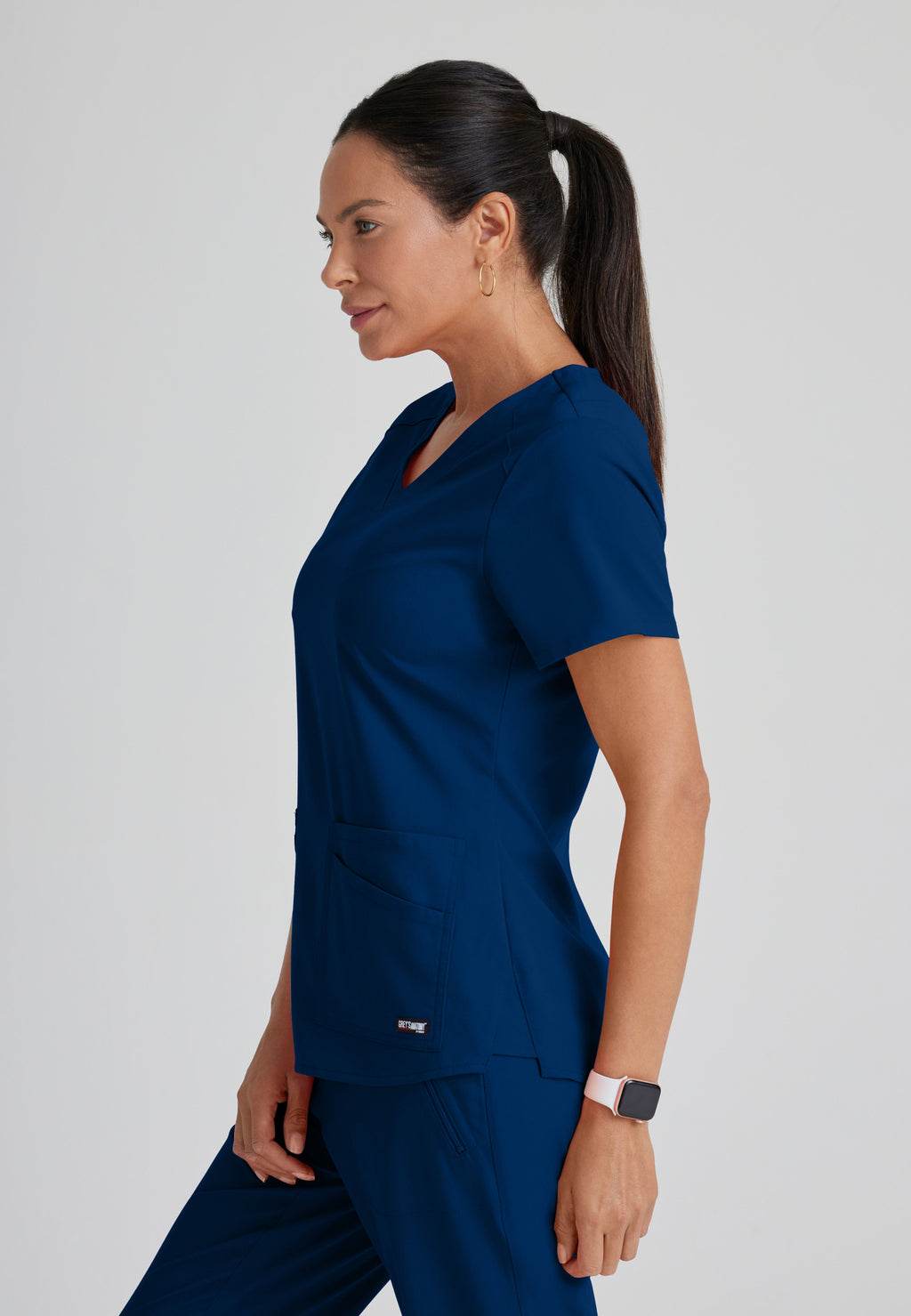 Side View of the Emma 4-Pocket V-Neck Scrub Top in Indigo from Grey's Anatomy™ by Barco Spandex Stretch