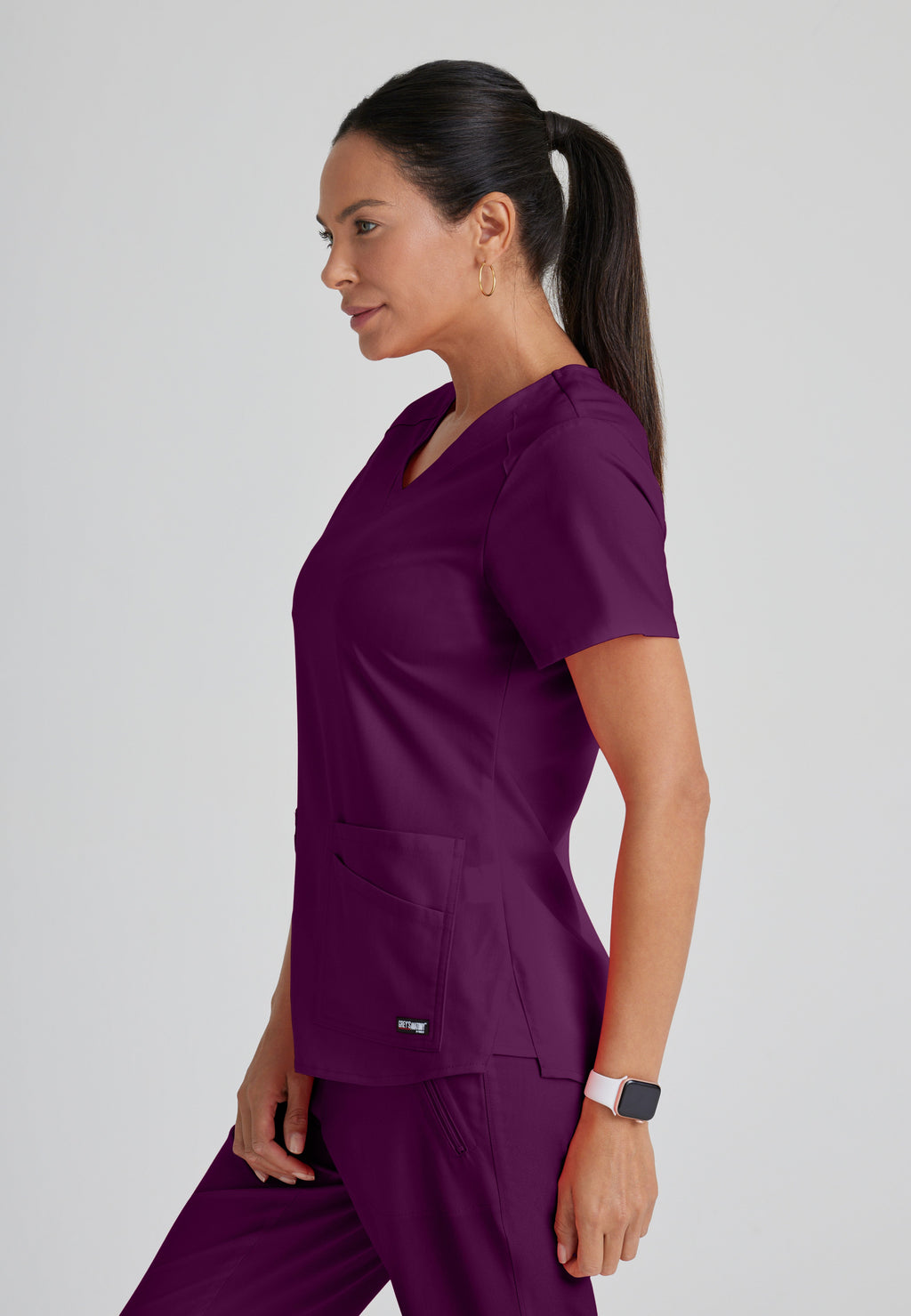 Side View of the Emma 4-Pocket V-Neck Scrub Top in Wine from Grey's Anatomy™ by Barco Spandex Stretch