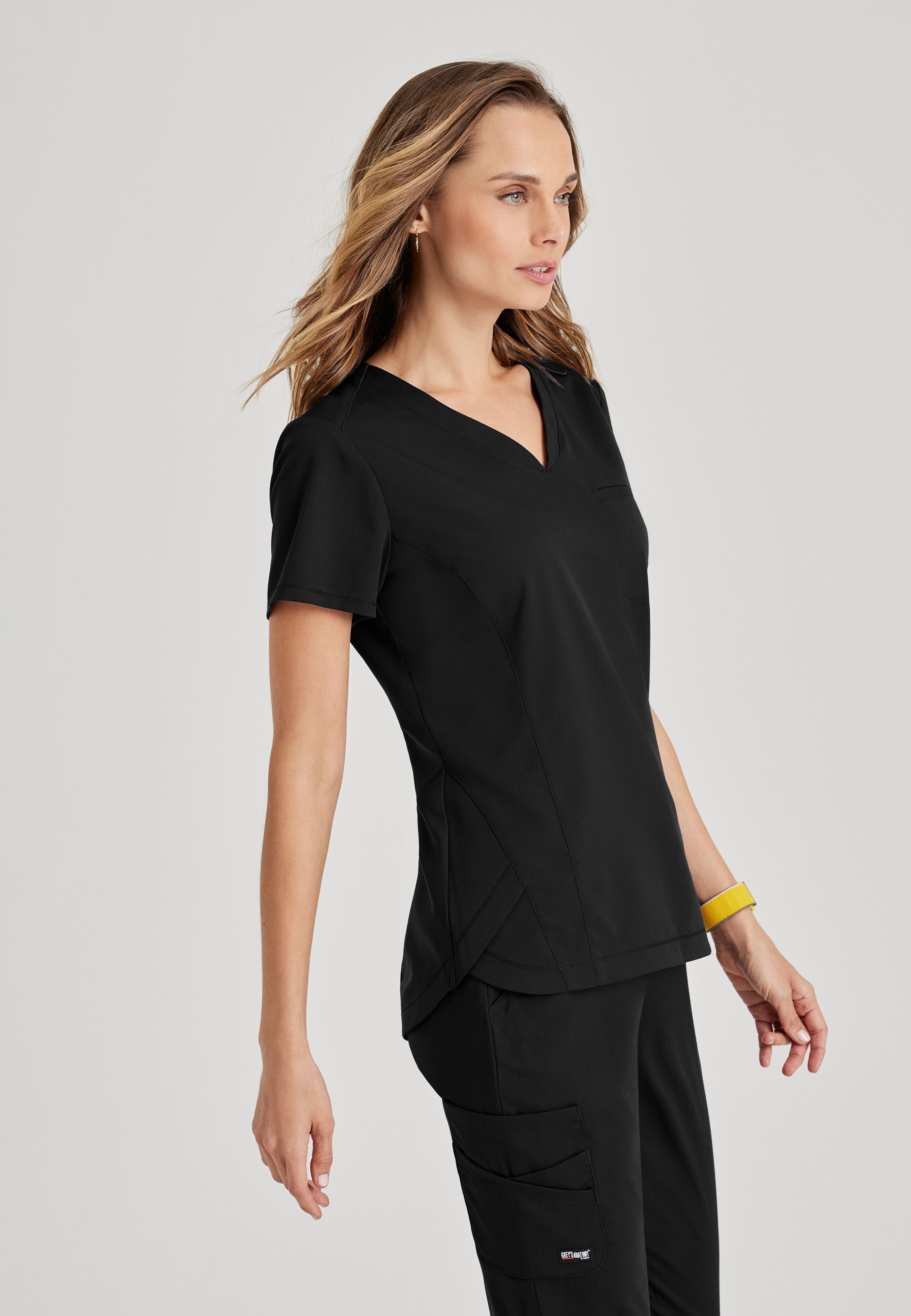 Side View of the Capri 2-Pocket Hourglass V-Neck Scrub Top in Black from Grey's Anatomy™ by Barco Spandex Stretch