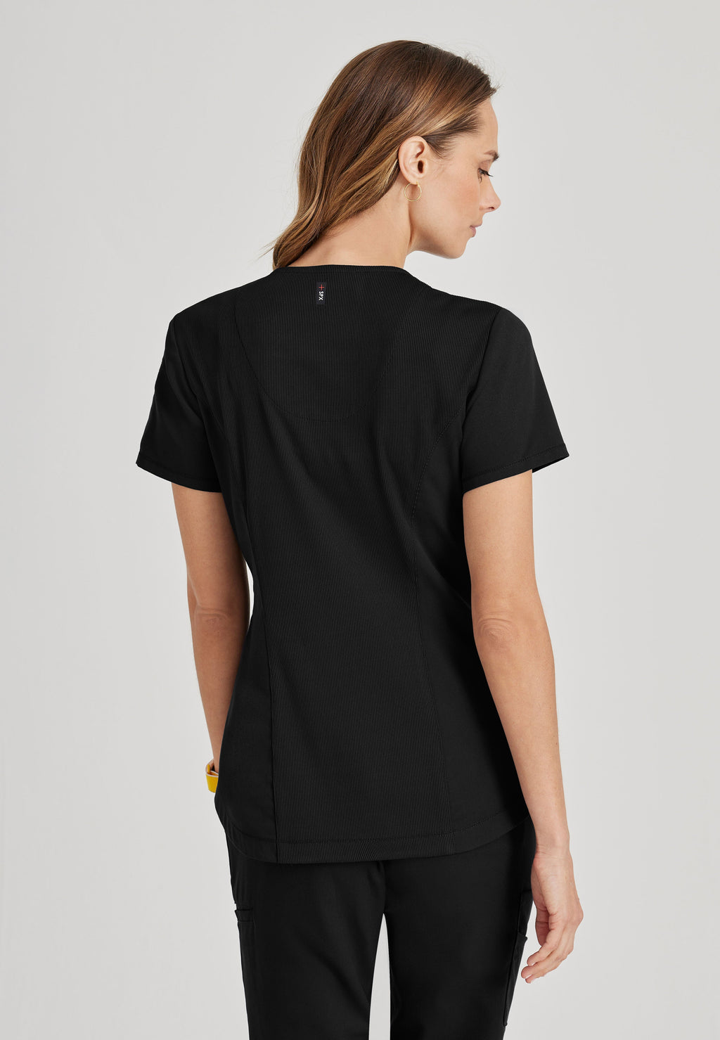 Back View of the Capri 2-Pocket Hourglass V-Neck Scrub Top in Black from Grey's Anatomy™ by Barco Spandex Stretch
