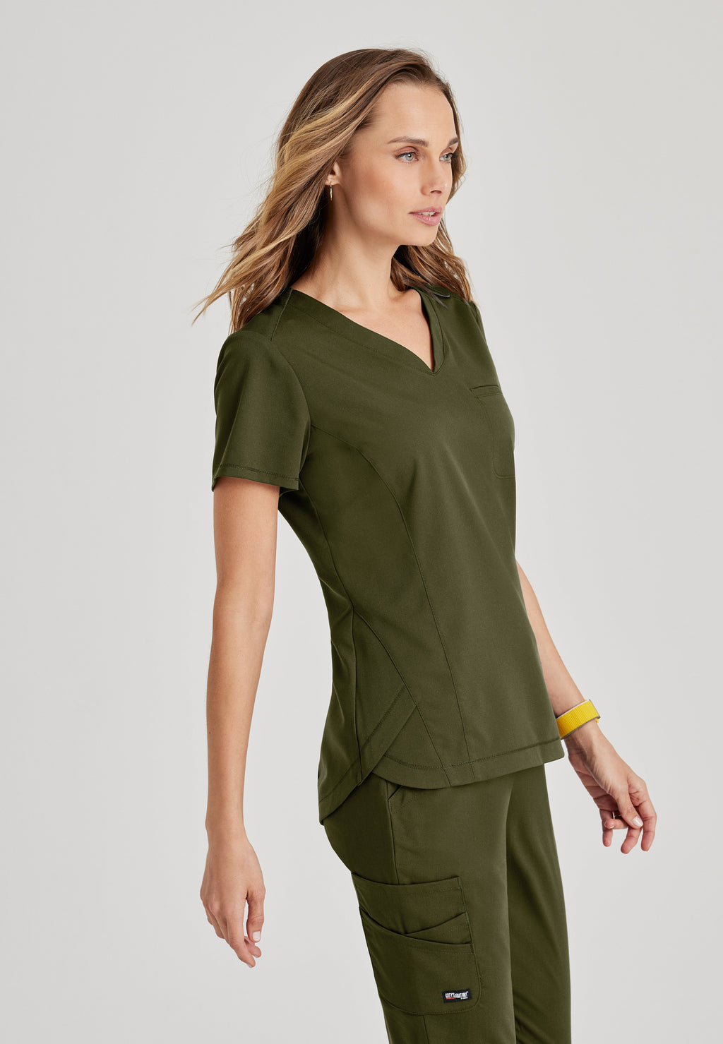 Side View of the Capri Tuck-in Scrub Top in Olive from Grey's Anatomy™ by Barco Spandex Stretch