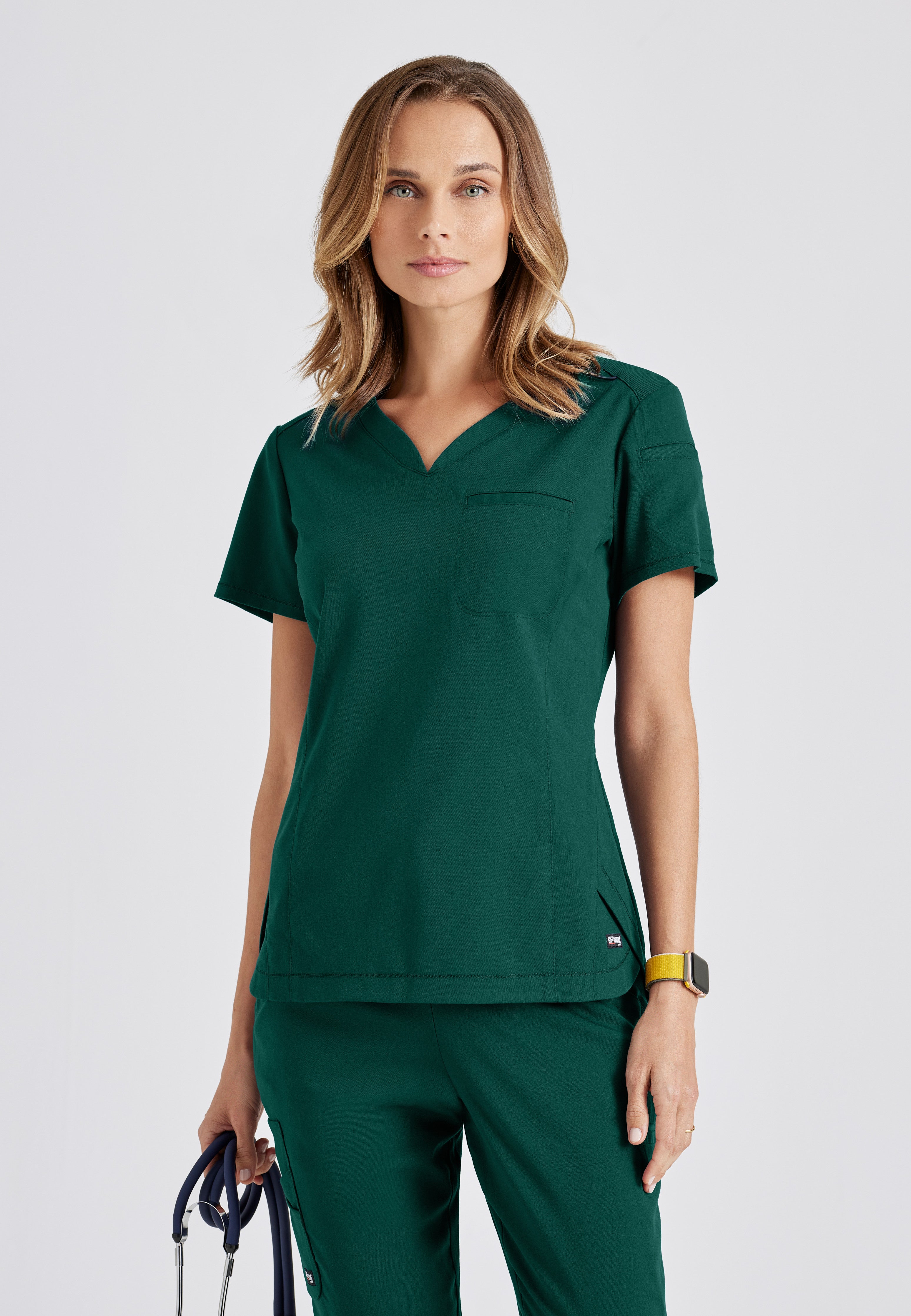 Front View of the Capri 2-Pocket Hourglass V-Neck Scrub Top in Hunter Green from Grey's Anatomy™ by Barco Spandex Stretch