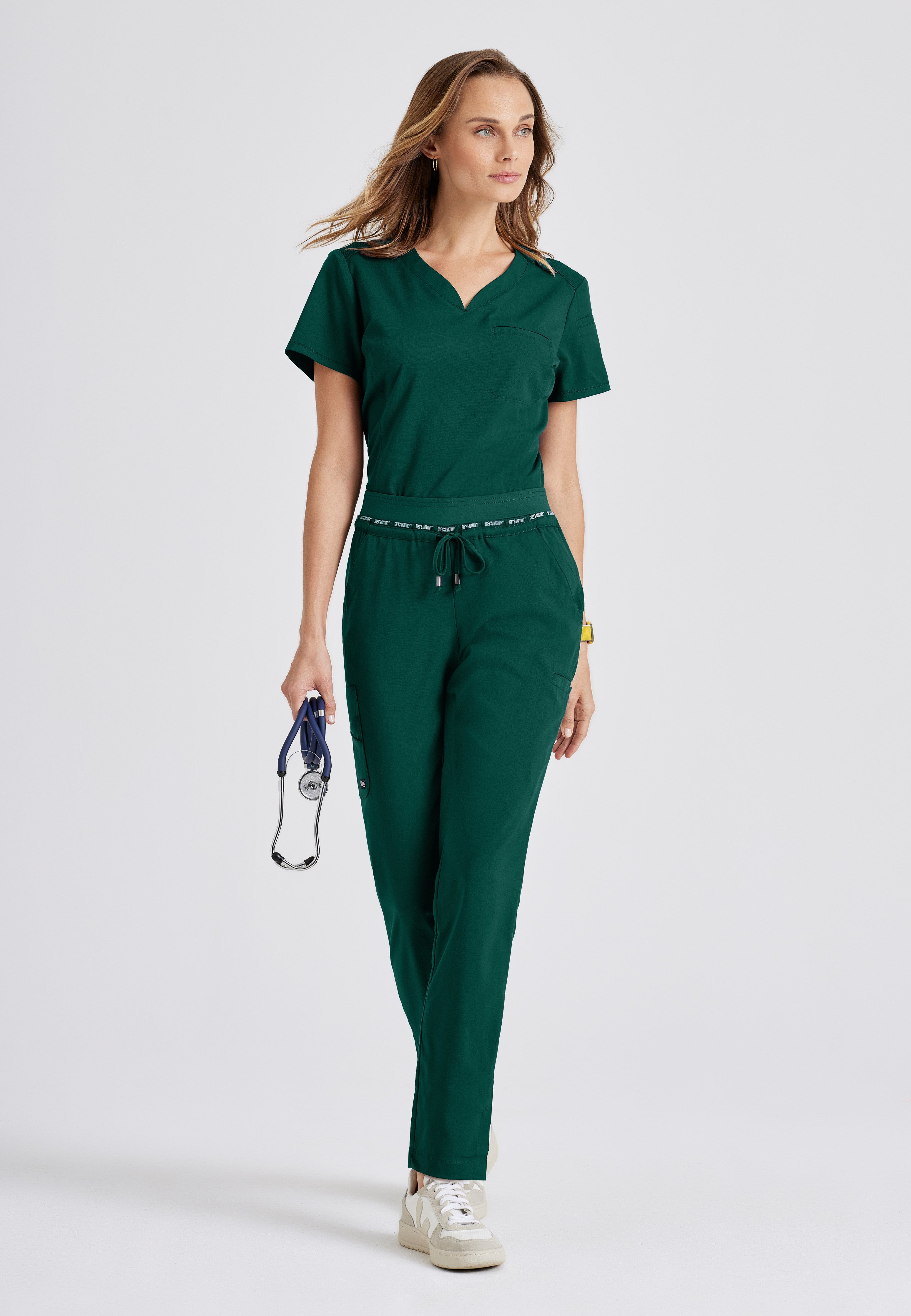 Full Body View of the Capri 2-Pocket Hourglass V-Neck Scrub Top in Hunter Green from Grey's Anatomy™ by Barco Spandex Stretch