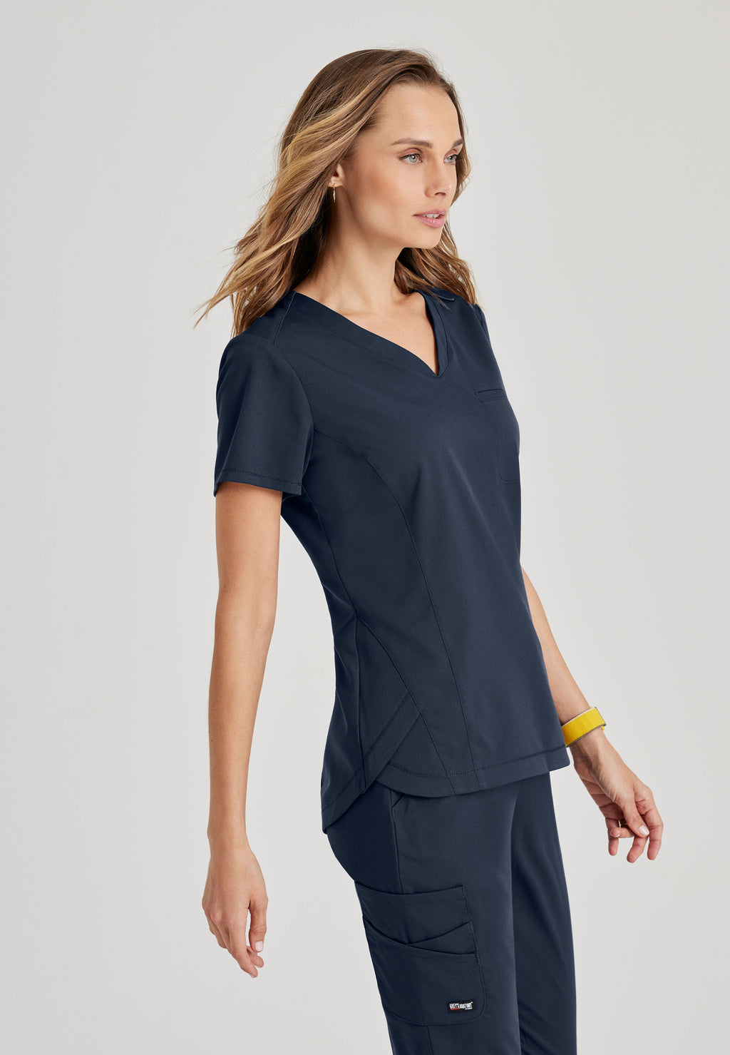 Side View of the Capri 2-Pocket Hourglass V-Neck Scrub Top in Steel from Grey's Anatomy™ by Barco Spandex Stretch