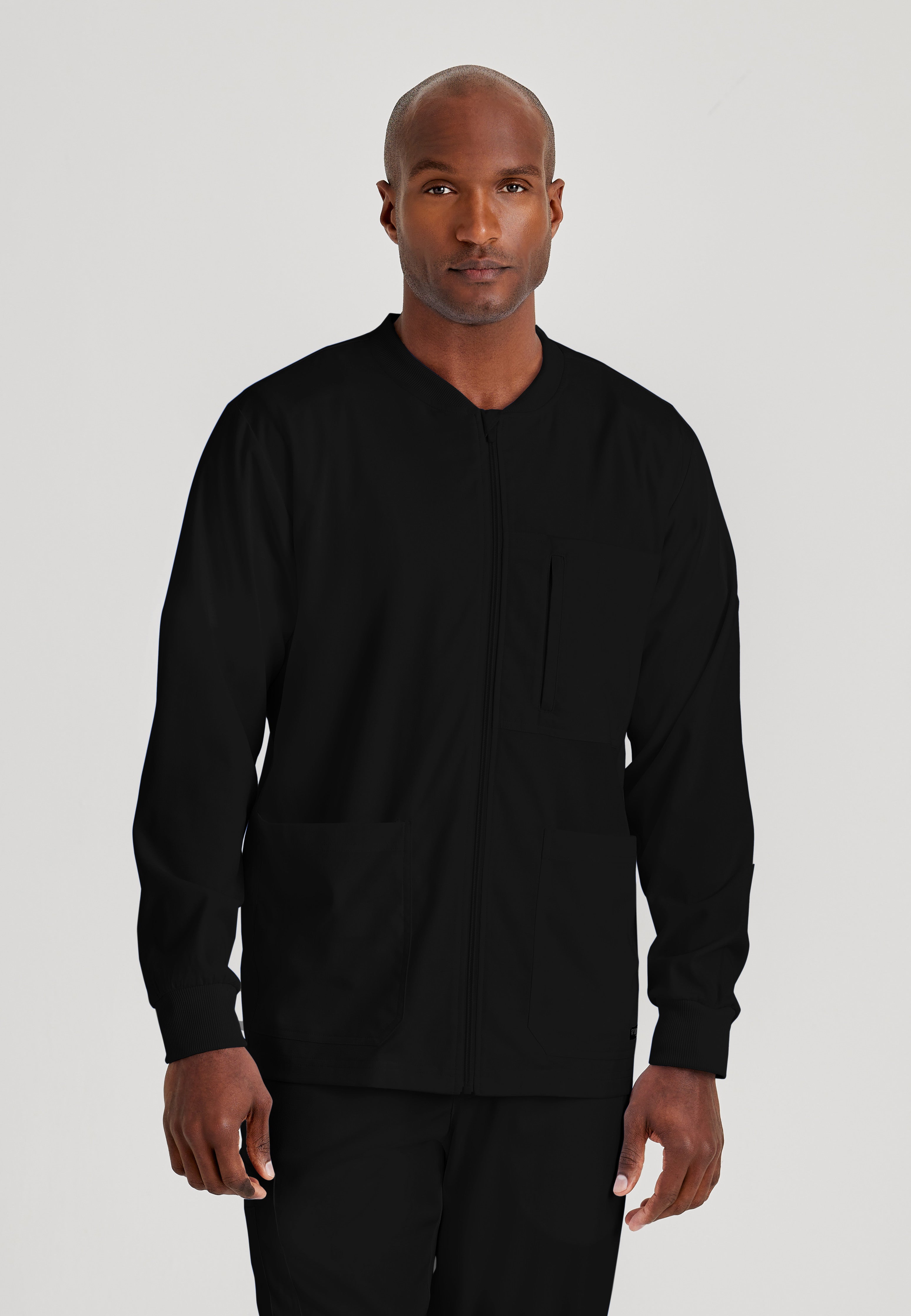 Front View of the React 5-Pocket Crewneck Warmup Scrub Jacket in Black from Grey's Anatomy™ by Barco Spandex Stretch