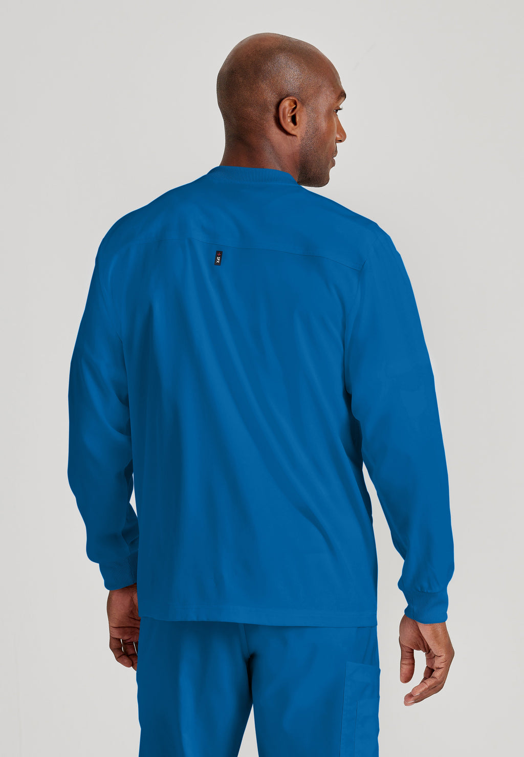 Back View of the React 5-Pocket Crewneck Warmup Scrub Jacket in New Royal from Grey's Anatomy™ by Barco Spandex Stretch
