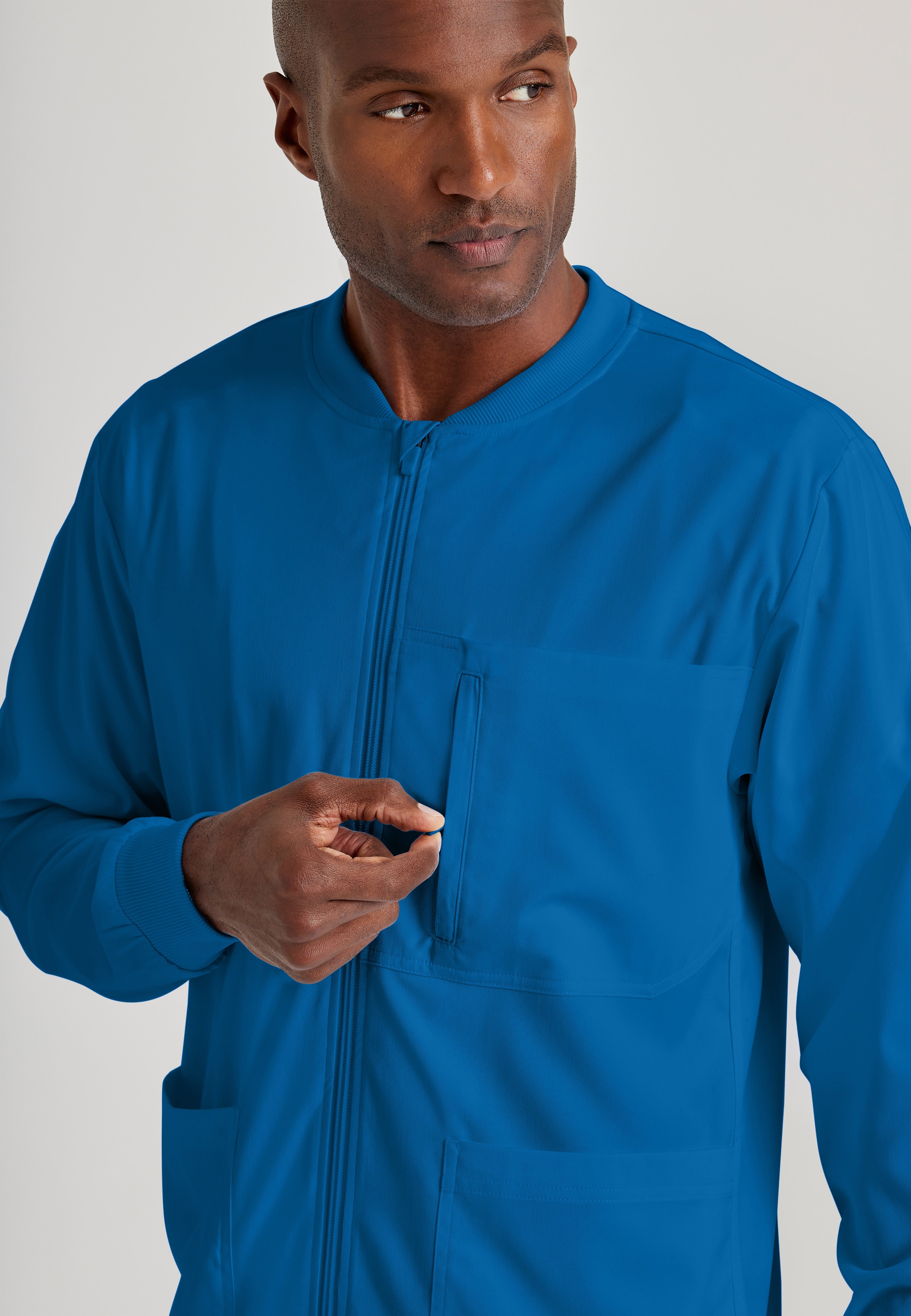 Detail Shot of the React 5-Pocket Crewneck Warmup Scrub Jacket in New Royal from Grey's Anatomy™ by Barco Spandex Stretch