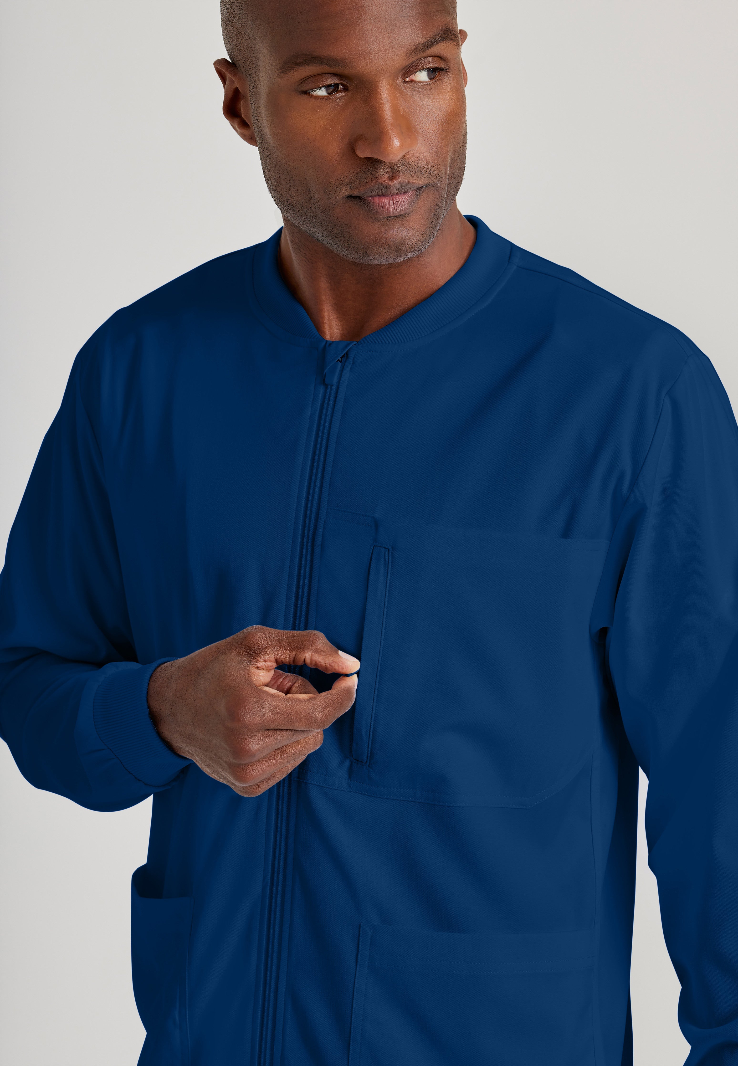 Detail Shot of the React 5-Pocket Crewneck Warmup Scrub Jacket in Indigo from Grey's Anatomy™ by Barco Spandex Stretch