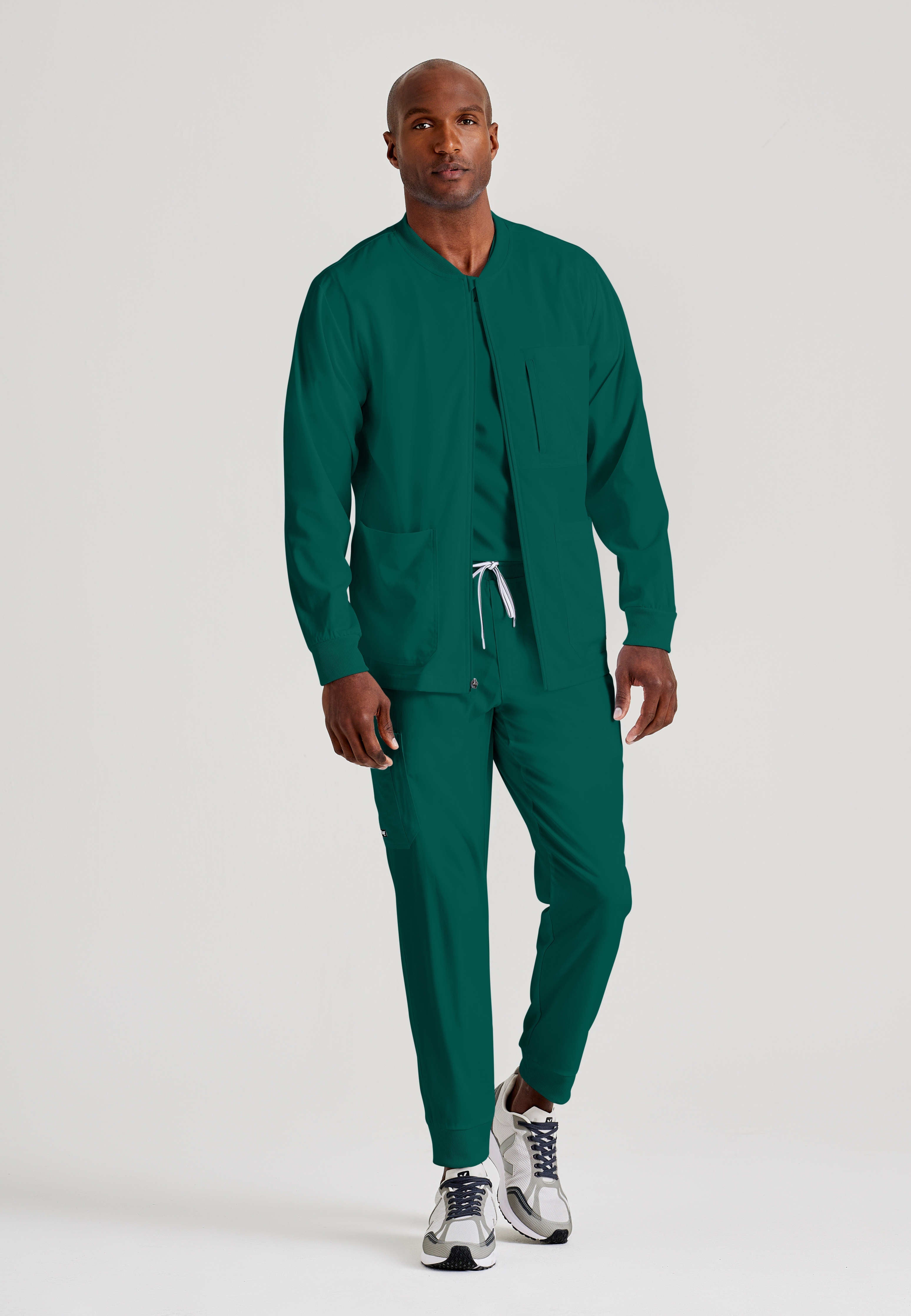 Full Body View of the React 5-Pocket Crewneck Warmup Scrub Jacket in Hunter Green from Grey's Anatomy™ by Barco Spandex Stretch