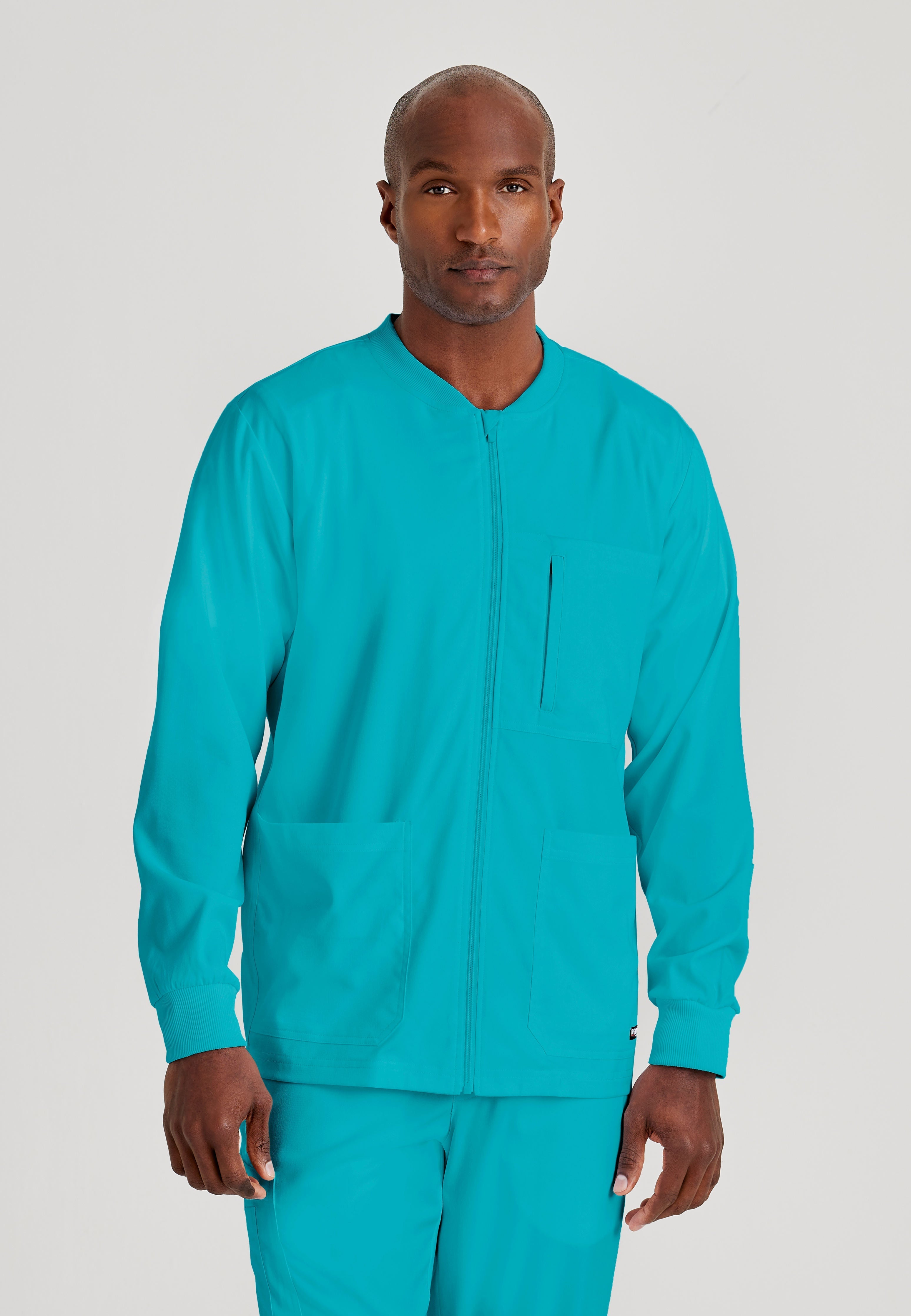 Grey's Anatomy Spandex-Stretch Men’s teal Warm-Up Scrub Jacket. Zip front with chin guard. Ribbed sleeve cuffs. 