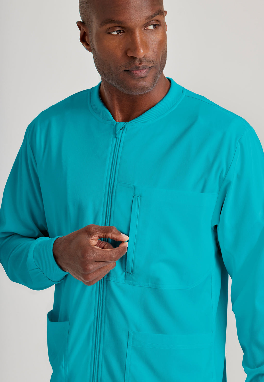 Grey's Anatomy Spandex-Stretch Men’s teal Warm-Up Scrub Jacket. Zip front with chin guard. Ribbed sleeve cuffs. 