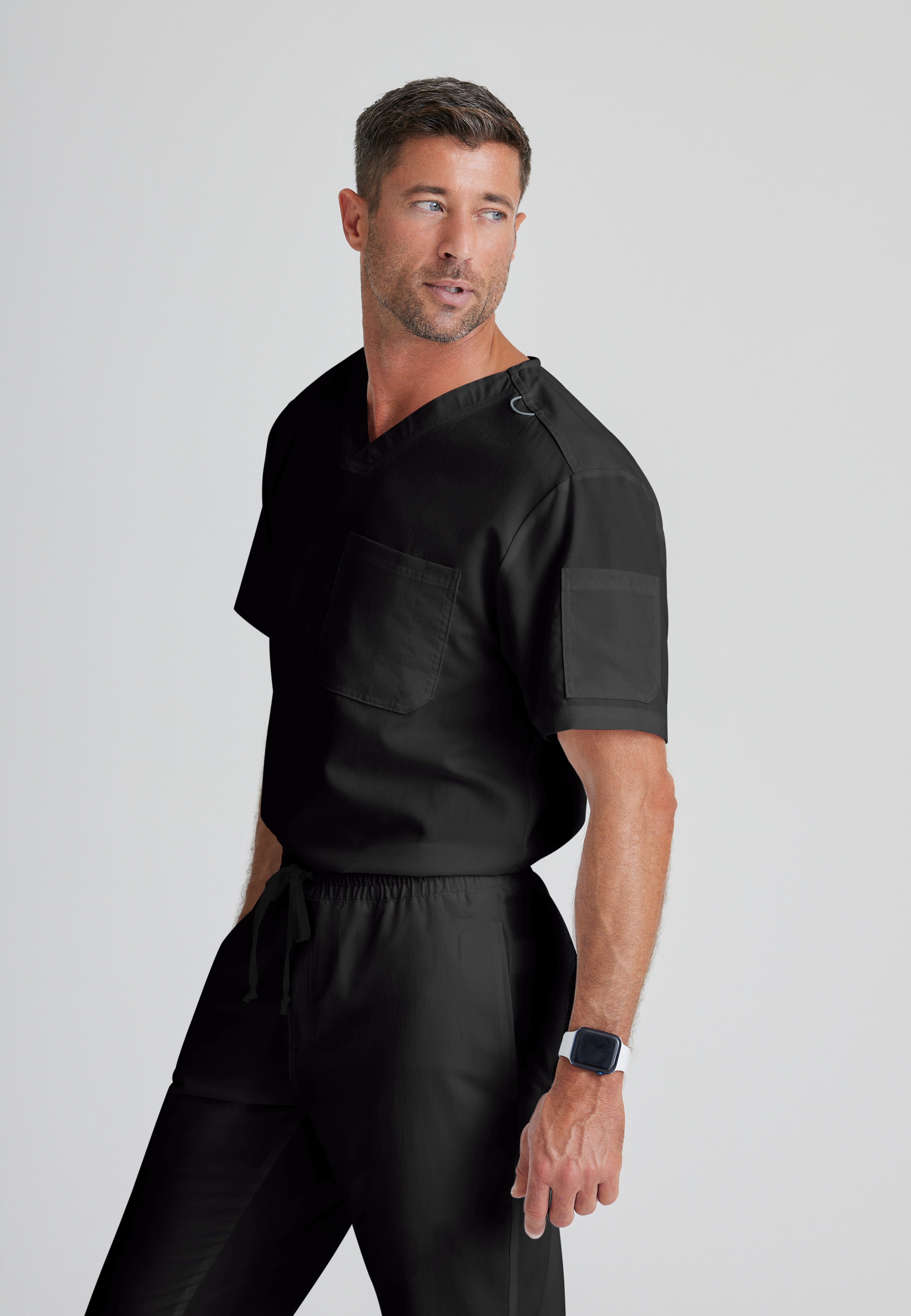 Side View of the Evan 2-Pocket V-Neck Scrub Top in Black from Grey's Anatomy™ by Barco Classic