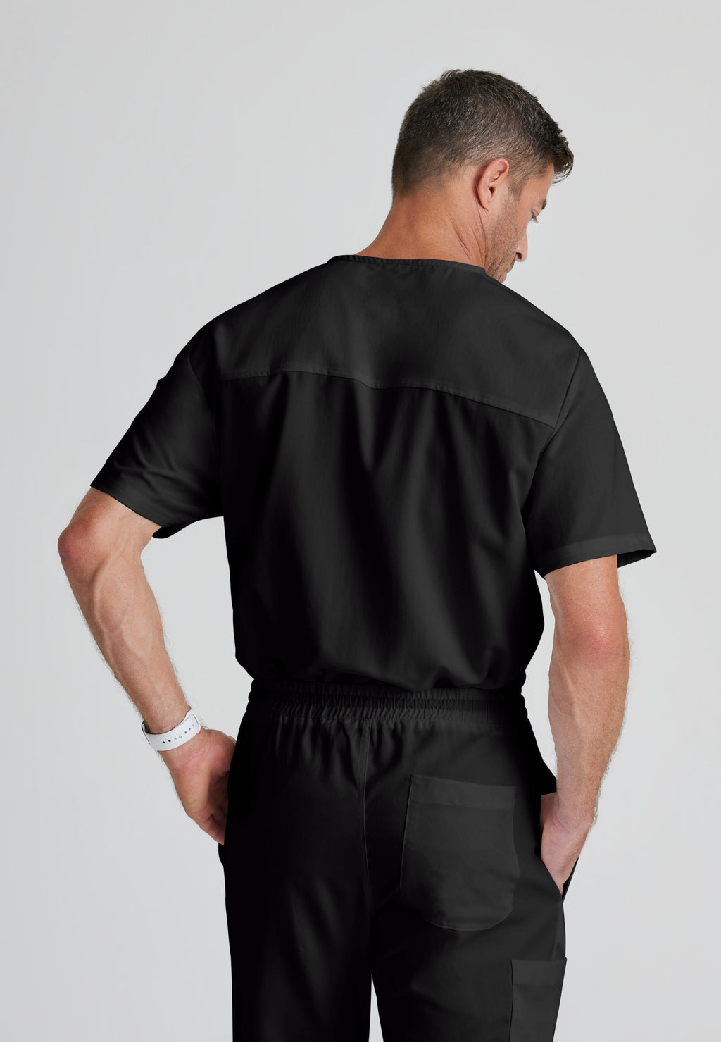 Back View of the Evan 2-Pocket V-Neck Scrub Top in Black from Grey's Anatomy™ by Barco Classic