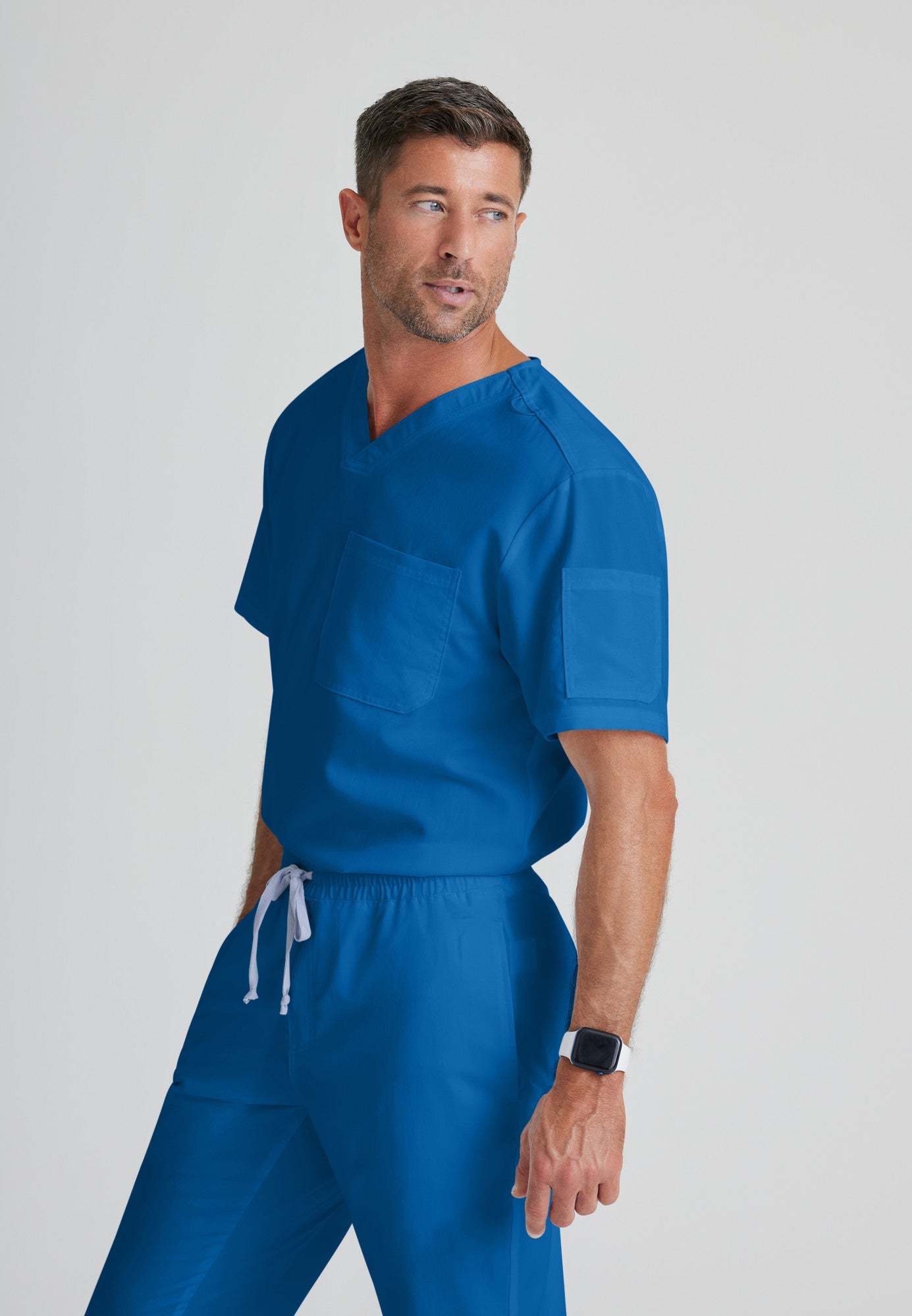 Side View of the Evan 2-Pocket V-Neck Scrub Top in New Royal from Grey's Anatomy™ by Barco Classic