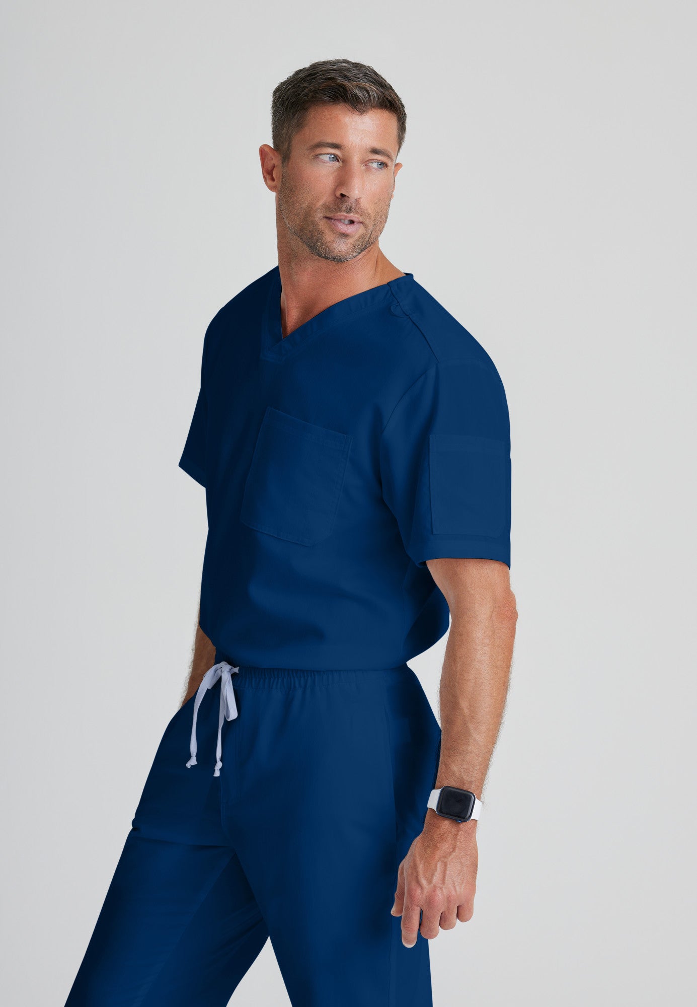 Side View of the Evan 2-Pocket V-Neck Scrub Top in Indigo from Grey's Anatomy™ by Barco Classic