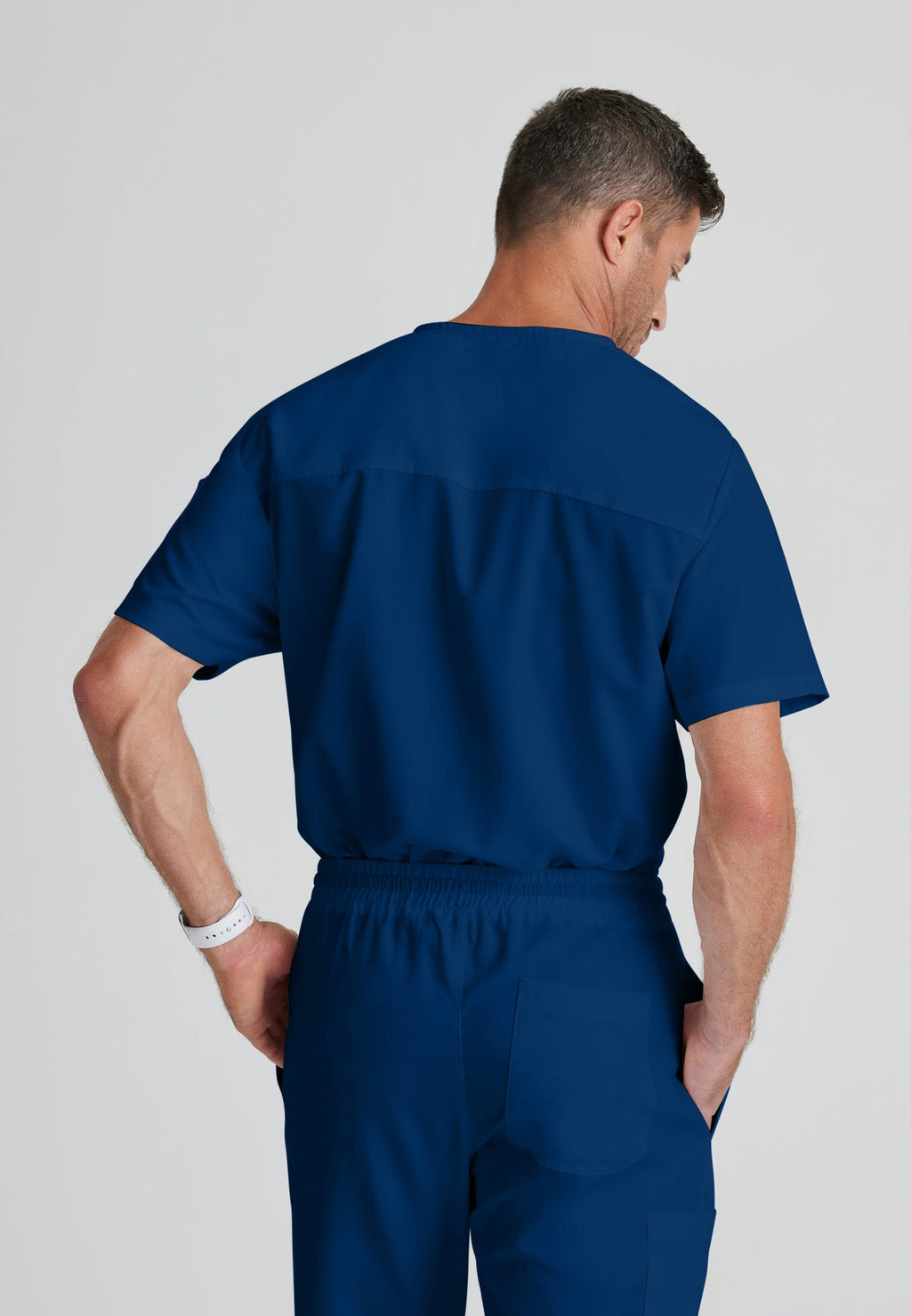 Back View of the Evan 2-Pocket V-Neck Scrub Top in Indigo from Grey's Anatomy™ by Barco Classic