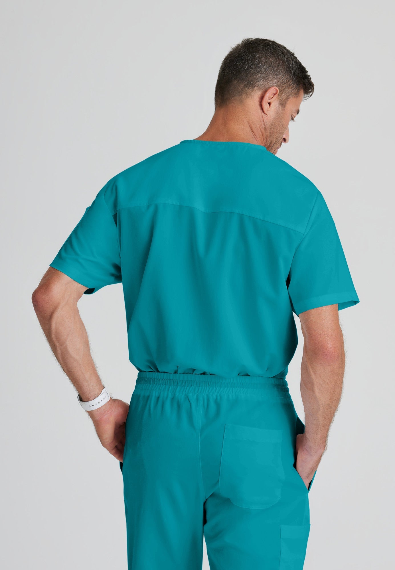 Back View of the Evan 2-Pocket V-Neck Scrub Top in Teal from Grey's Anatomy™ by Barco Classic