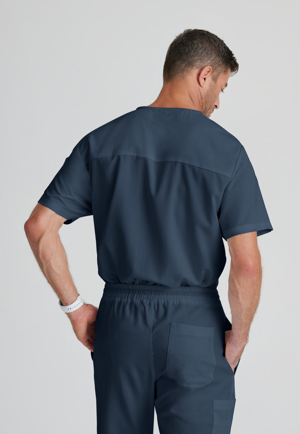 Back View of the Evan 2-Pocket V-Neck Scrub Top in Steel from Grey's Anatomy™ by Barco Classic