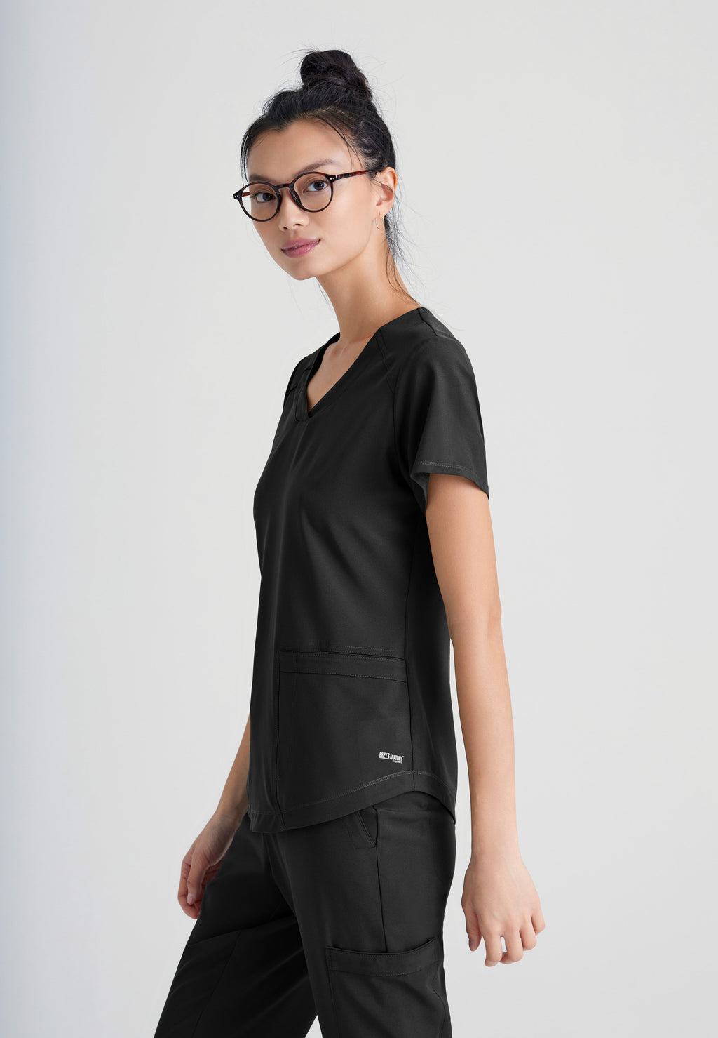 Side View of the Rhythm 2-Pocket Ciclo® Scrub Top in Black from Grey's Anatomy™ by Barco Evolve