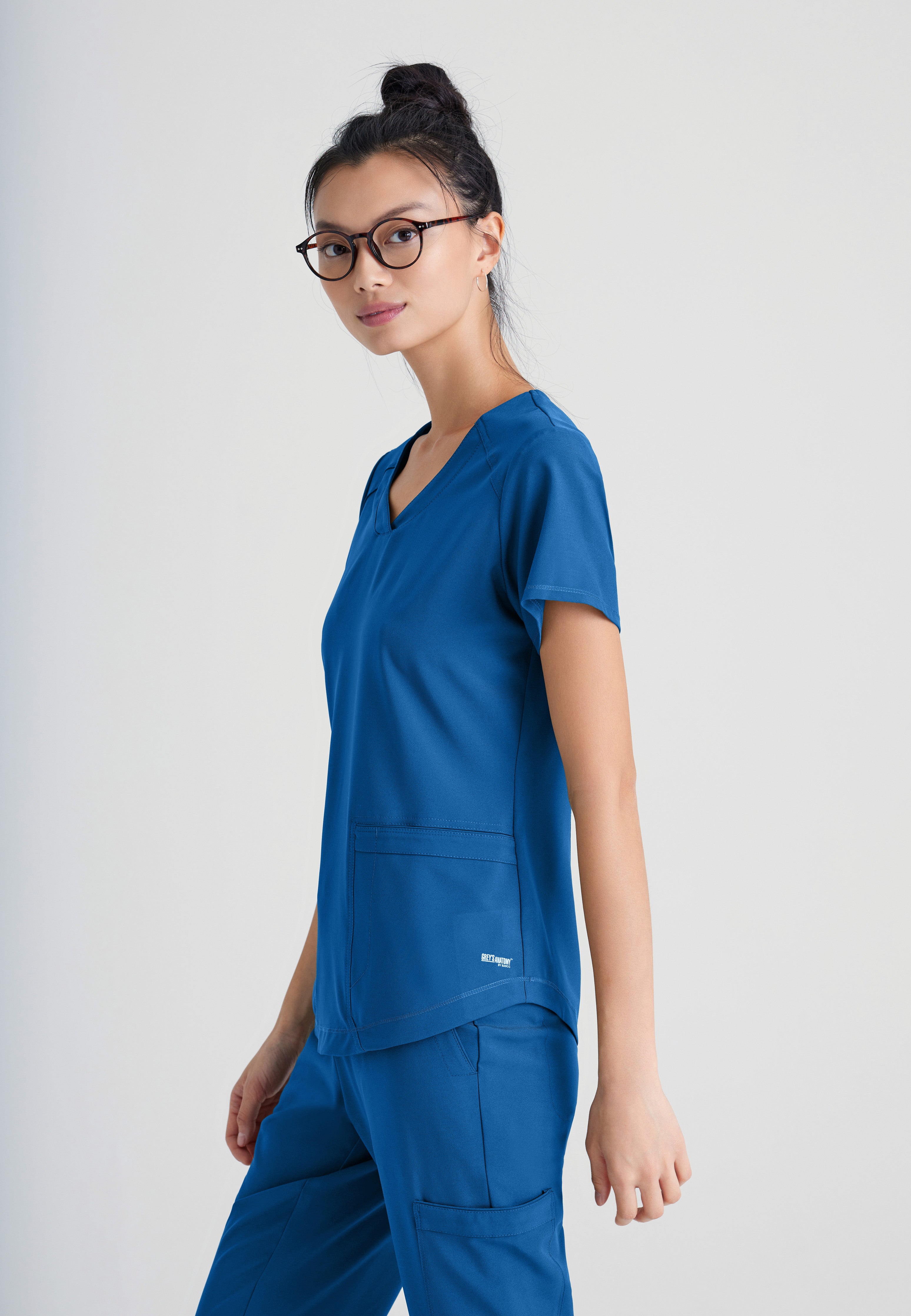 Side View of the Rhythm 2-Pocket Ciclo® Scrub Top in New Royal from Grey's Anatomy™ by Barco Evolve