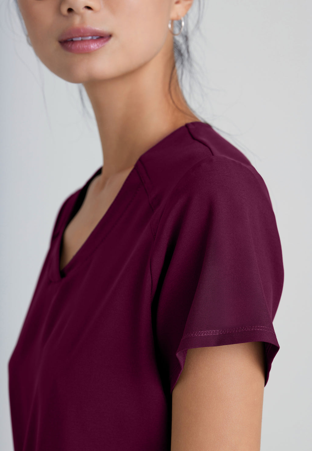 Detail Shot of the Rhythm 2-Pocket Ciclo® Scrub Top in Wine from Grey's Anatomy™ by Barco Evolve