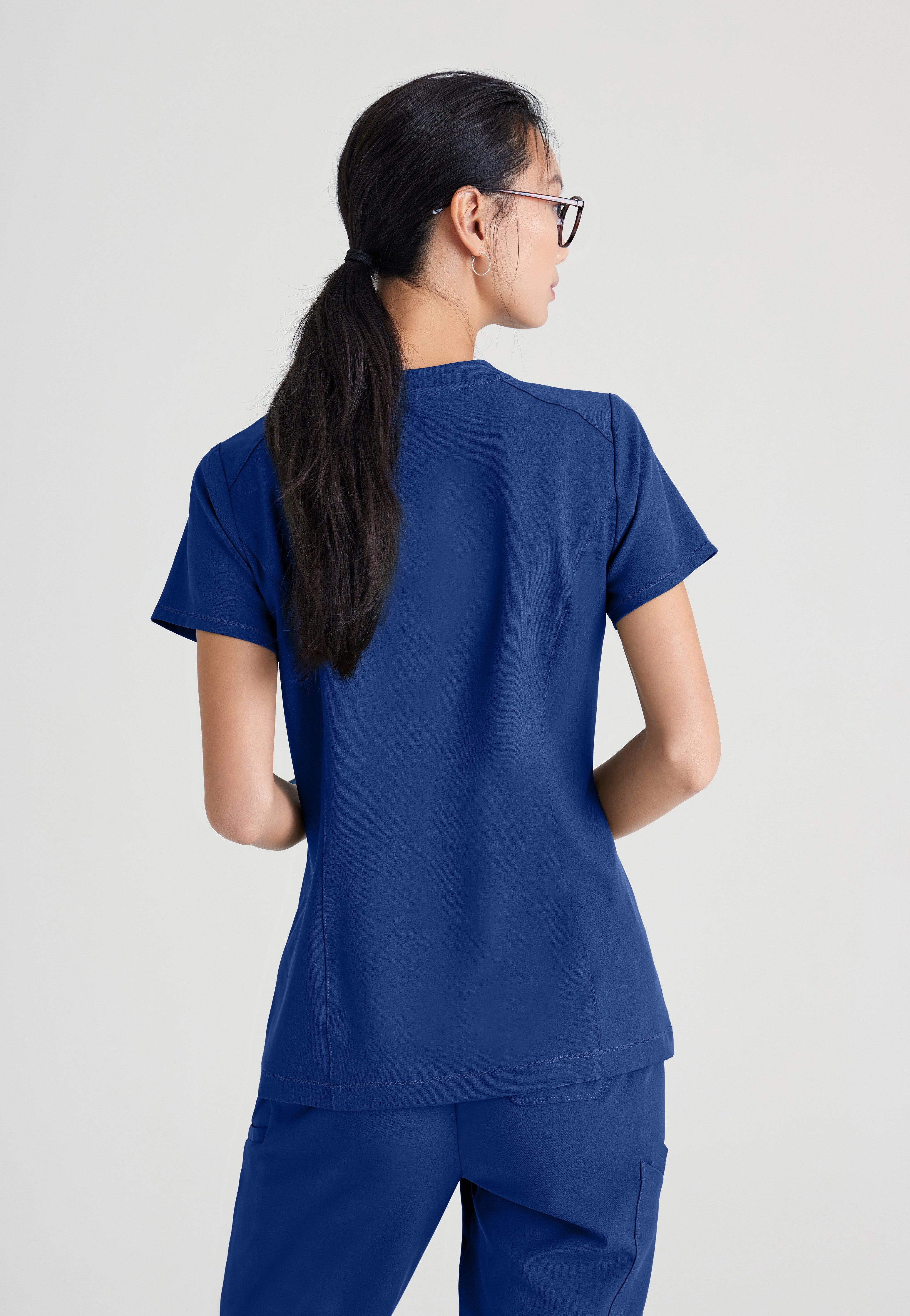 Back View of the Sway 1-Pocket Banded V-Neck Ciclo® Scrub Top in Indigo from Grey's Anatomy™ by Barco Evolve