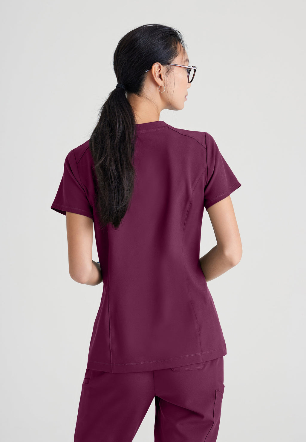 Back View of the Sway 1-Pocket Banded V-Neck Ciclo® Scrub Top in Wine from Grey's Anatomy™ by Barco Evolve
