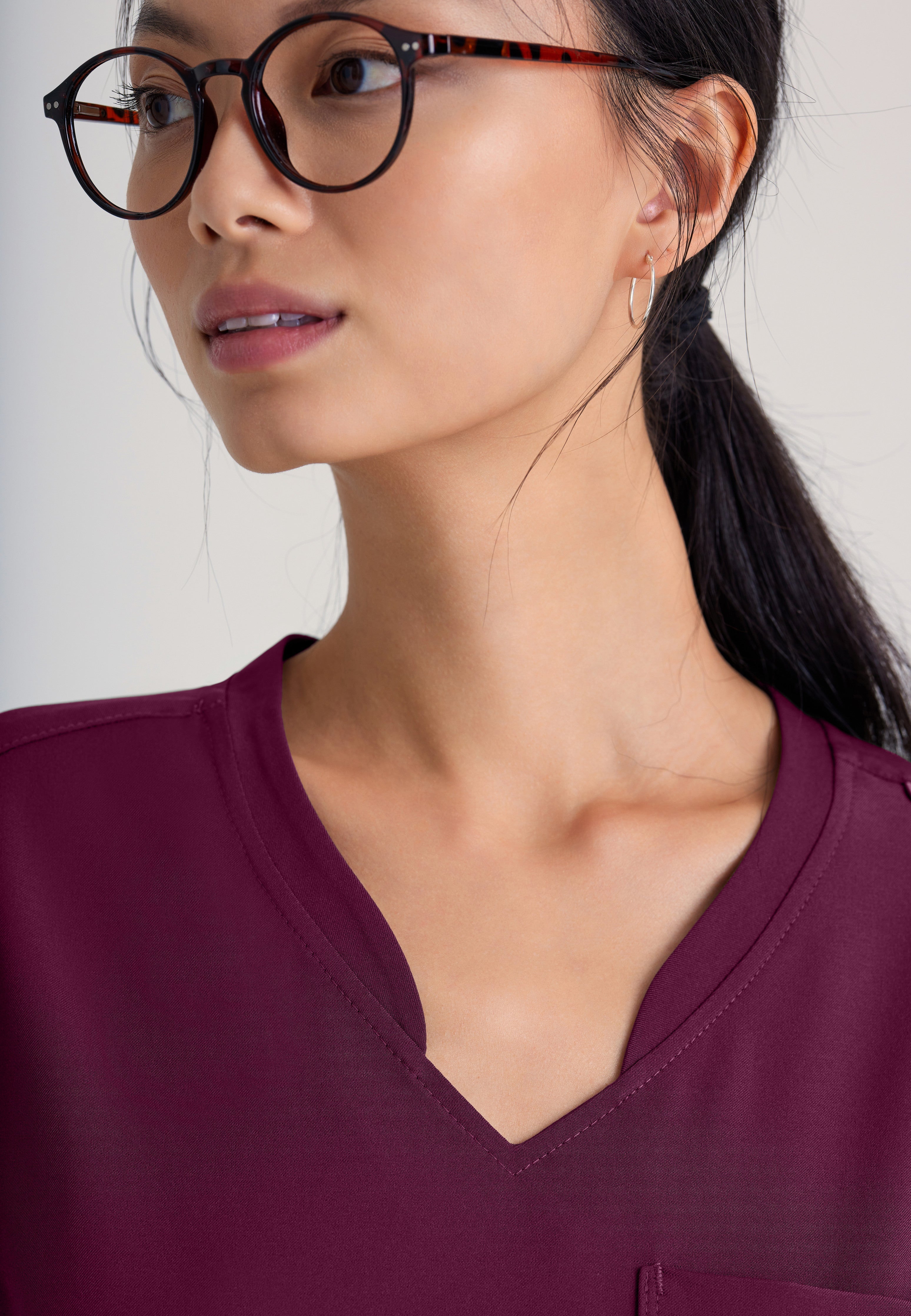 Detail Shot of the Sway 1-Pocket Banded V-Neck Ciclo® Scrub Top in Wine from Grey's Anatomy™ by Barco Evolve