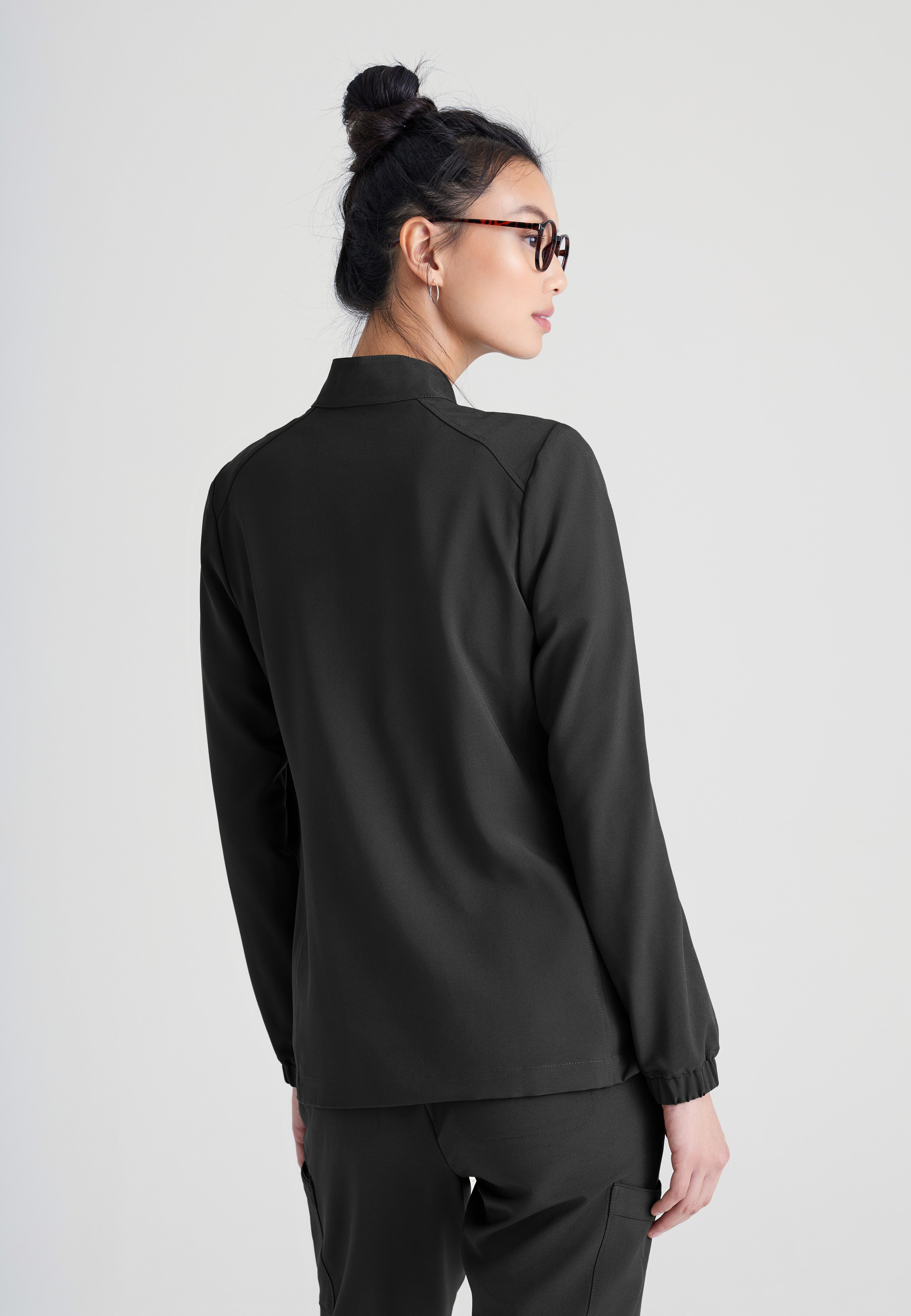 Back View of the Virtue 3-Pocket Stand-Up Collar Ciclo® Scrub Jacket in Black from Grey's Anatomy™ by Barco Evolve