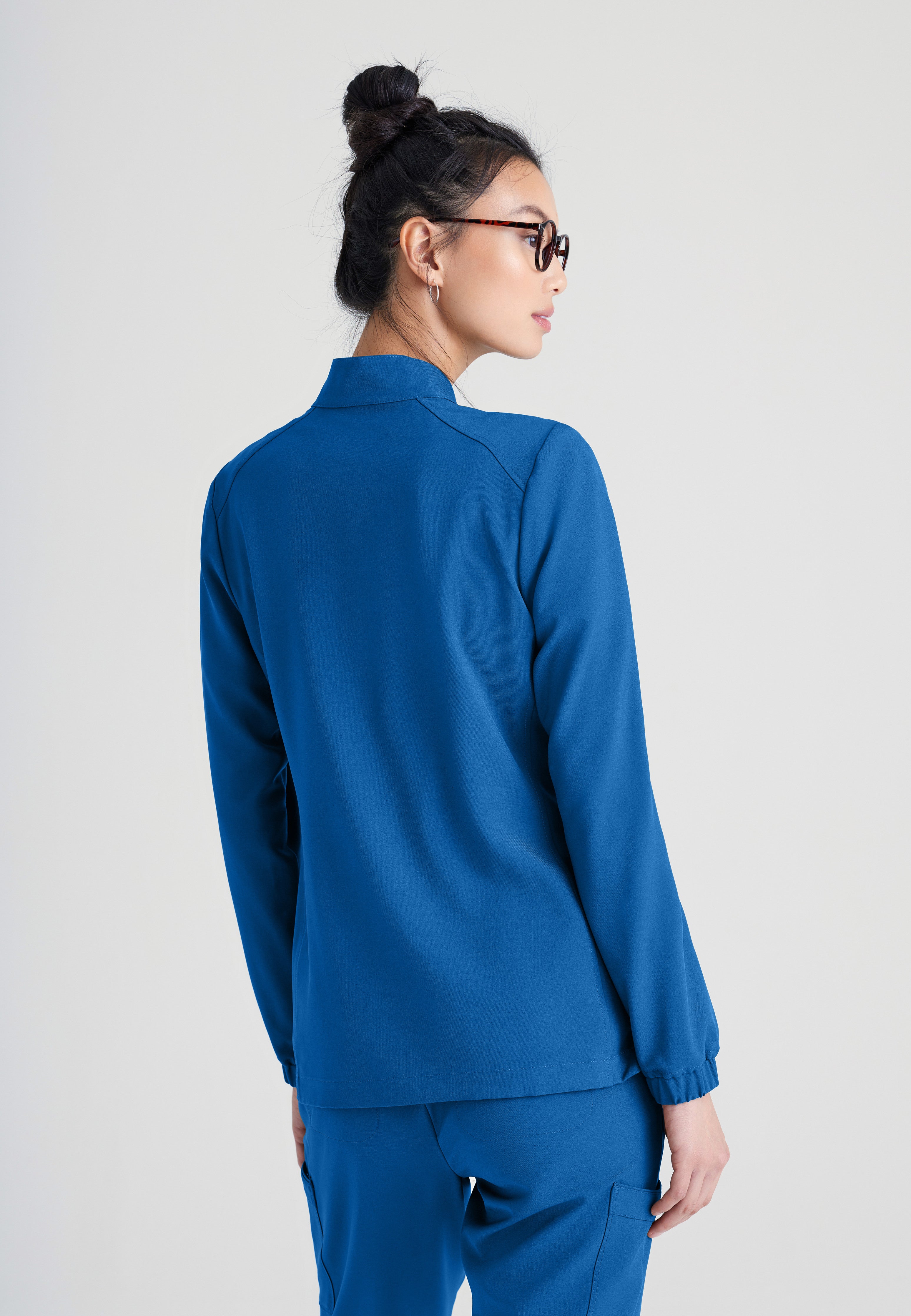 Back View of the Virtue 3-Pocket Stand-Up Collar Ciclo® Scrub Jacket in New Royal from Grey's Anatomy™ by Barco Evolve