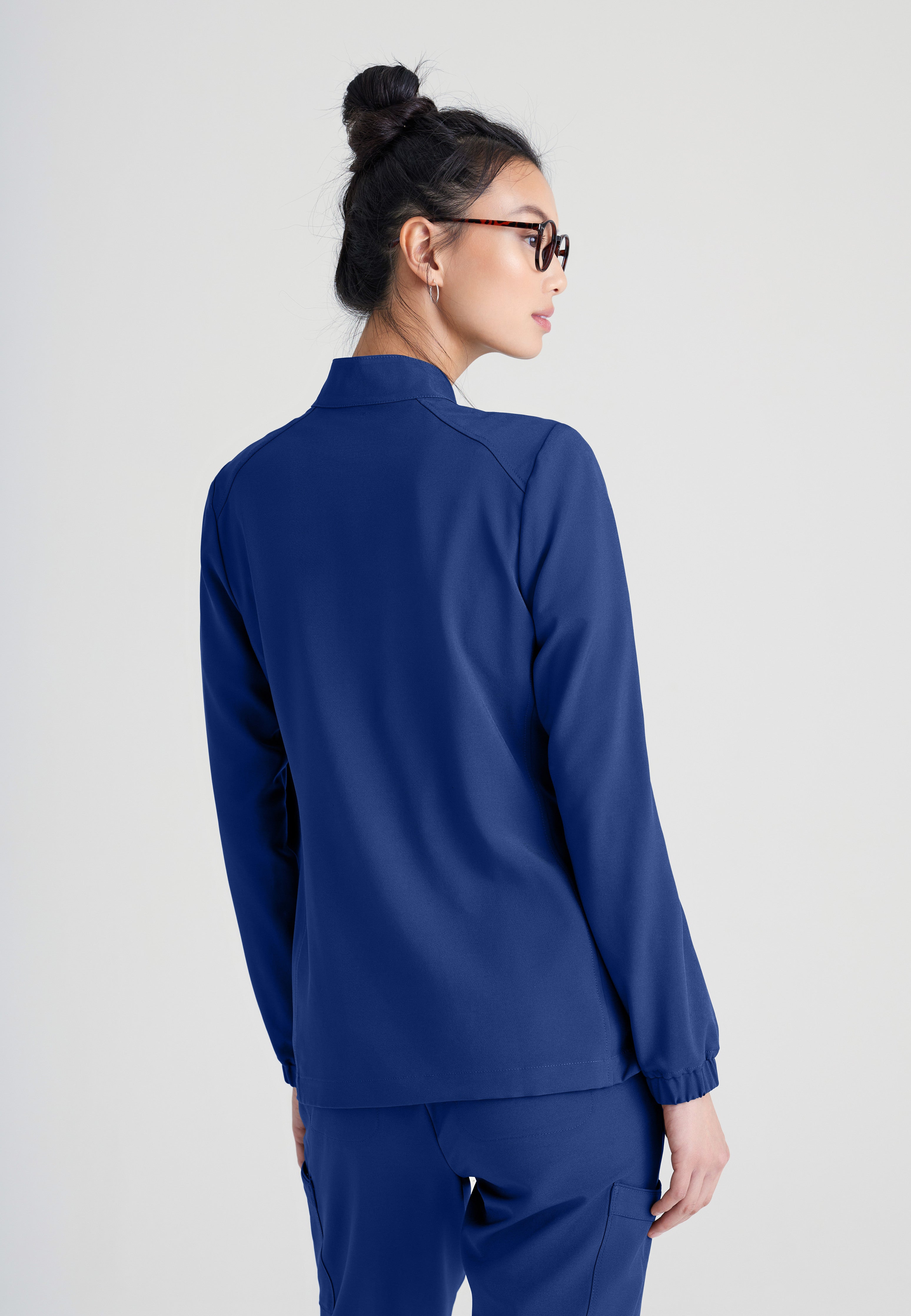 Back View of the Virtue 3-Pocket Stand-Up Collar Ciclo® Scrub Jacket in Indigo from Grey's Anatomy™ by Barco Evolve