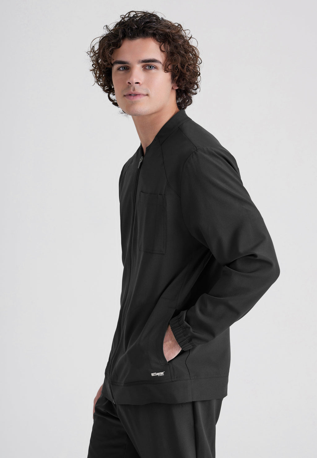 Side View of the Cycle 3-Pocket Crewneck Ciclo® Scrub Jacket in Black from Grey's Anatomy™ by Barco Evolve