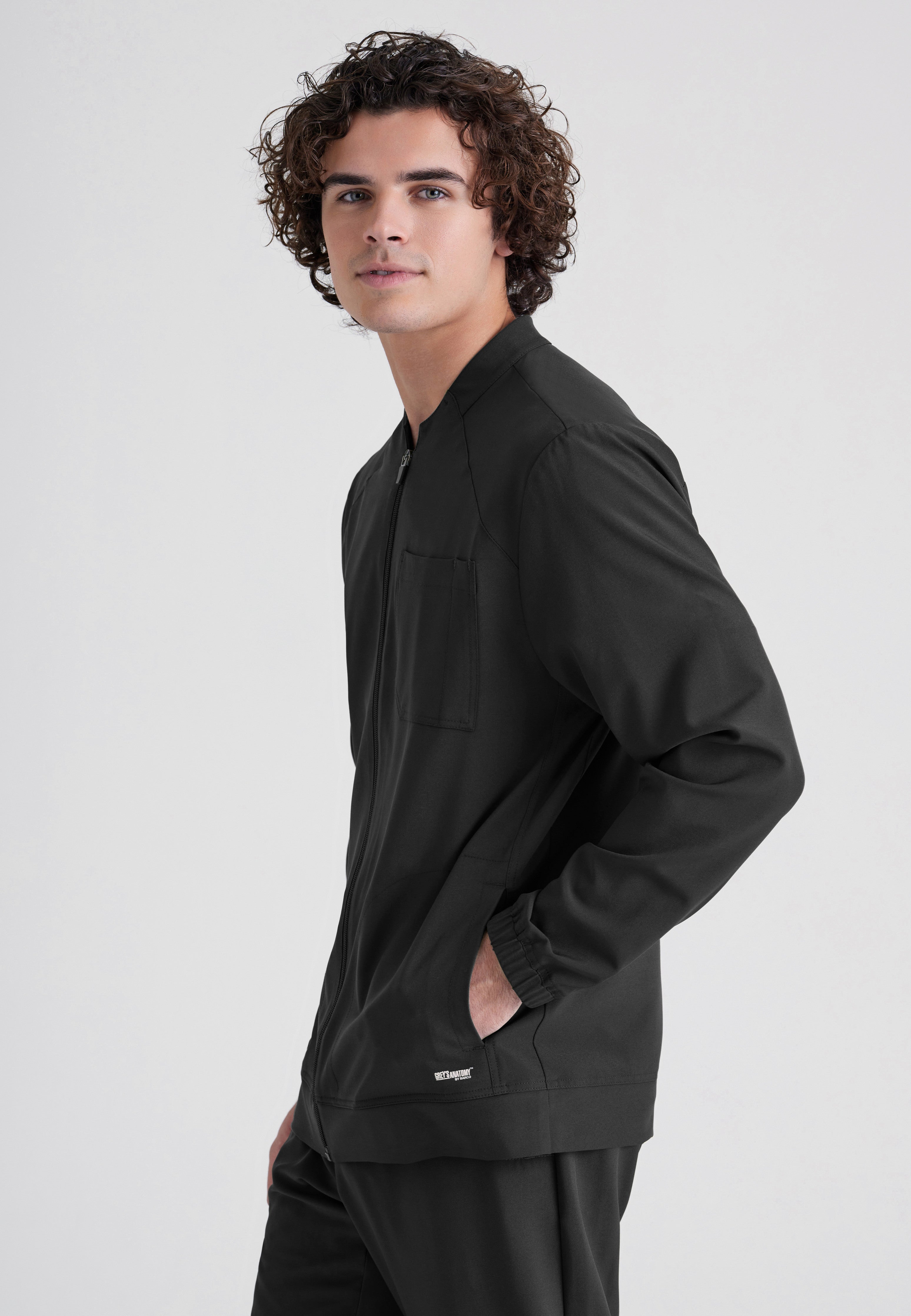Side View of the Cycle 3-Pocket Crewneck Ciclo® Scrub Jacket in Black from Grey's Anatomy™ by Barco Evolve