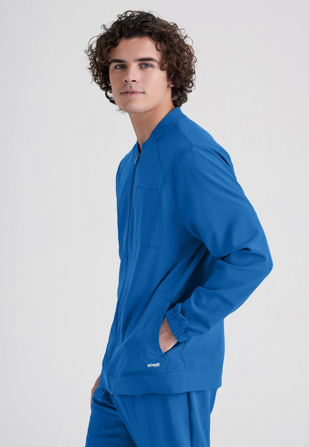 Side View of the Cycle 3-Pocket Crewneck Ciclo® Scrub Jacket in New Royal from Grey's Anatomy™ by Barco Evolve