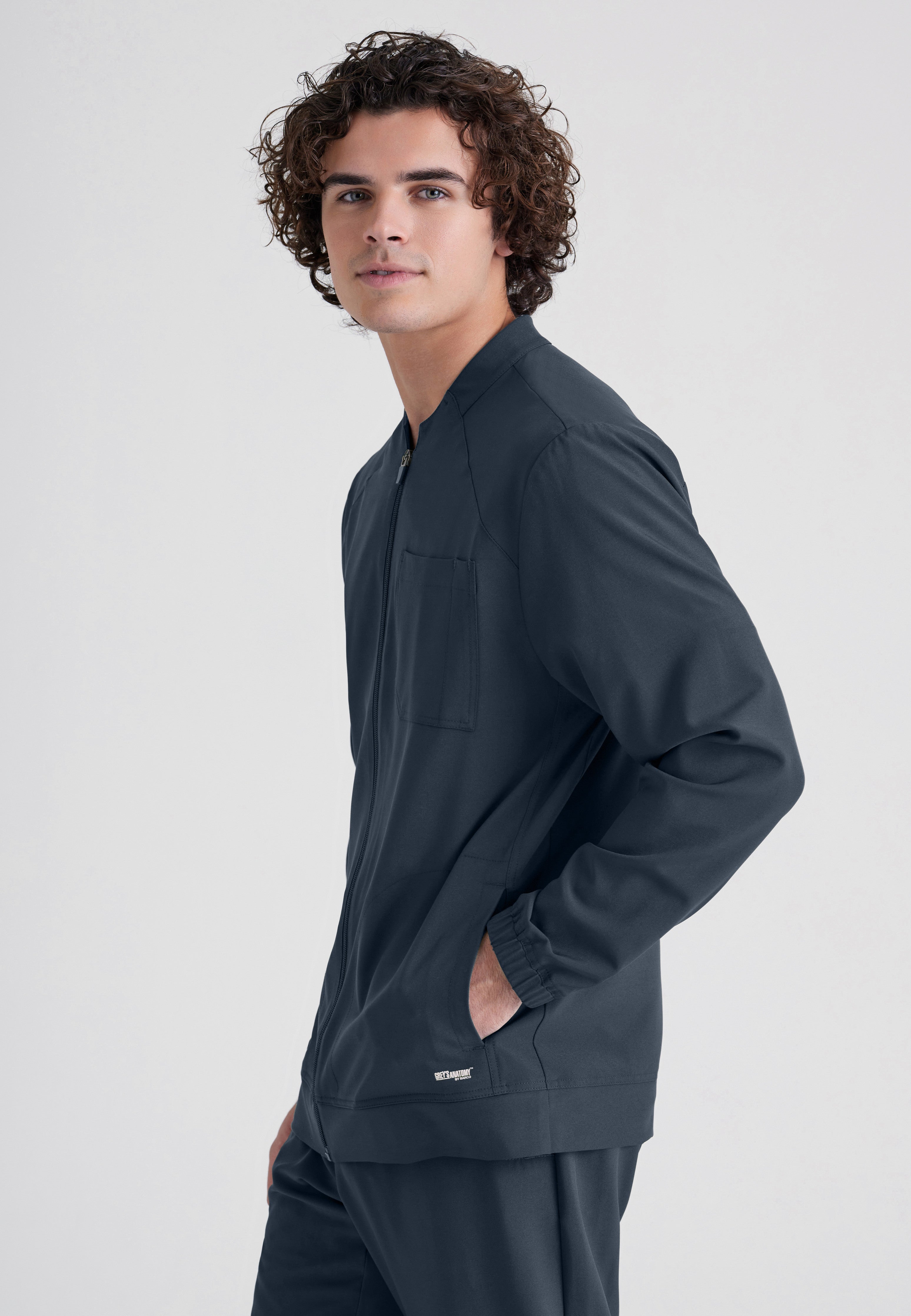 Side View of the Cycle 3-Pocket Crewneck Ciclo® Scrub Jacket in Steel from Grey's Anatomy™ by Barco Evolve