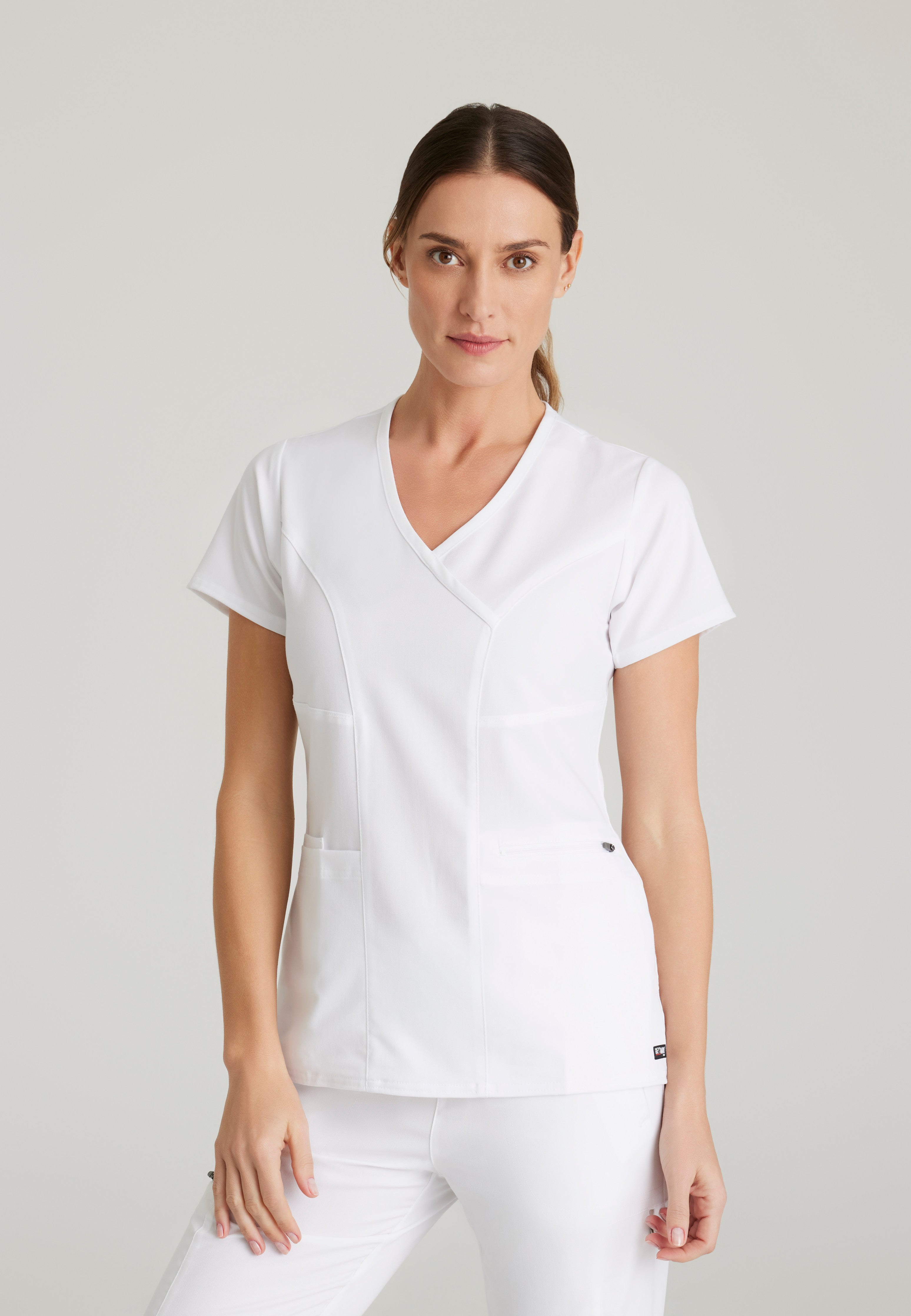 Front View of the Kim 3-Pocket Crossover V-Neck Scrub Top in White from Grey's Anatomy™ by Barco Spandex Stretch